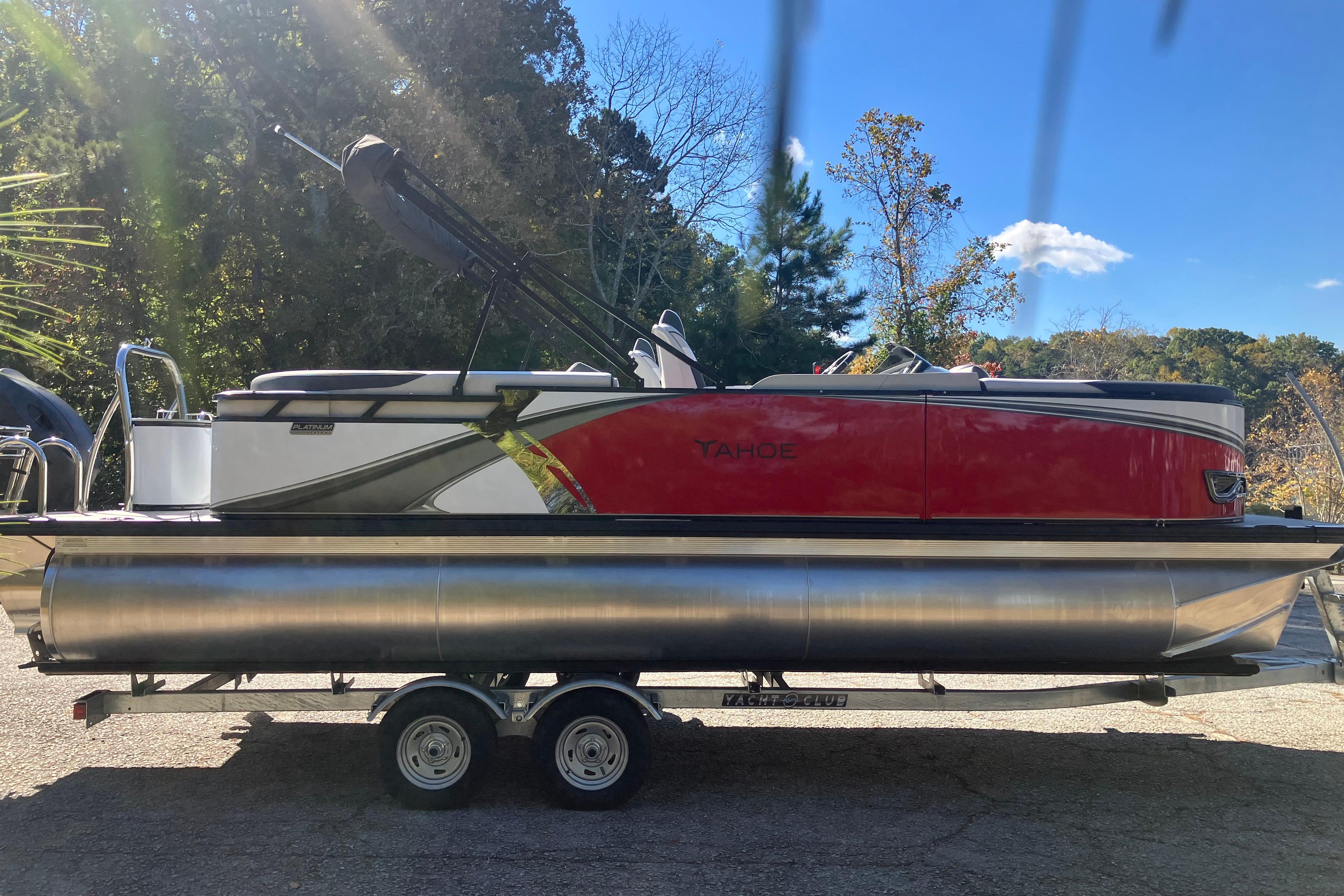 2026 Tahoe Pontoon LTZ Quad Lounger on trailer, red and silver design, outdoor setting.