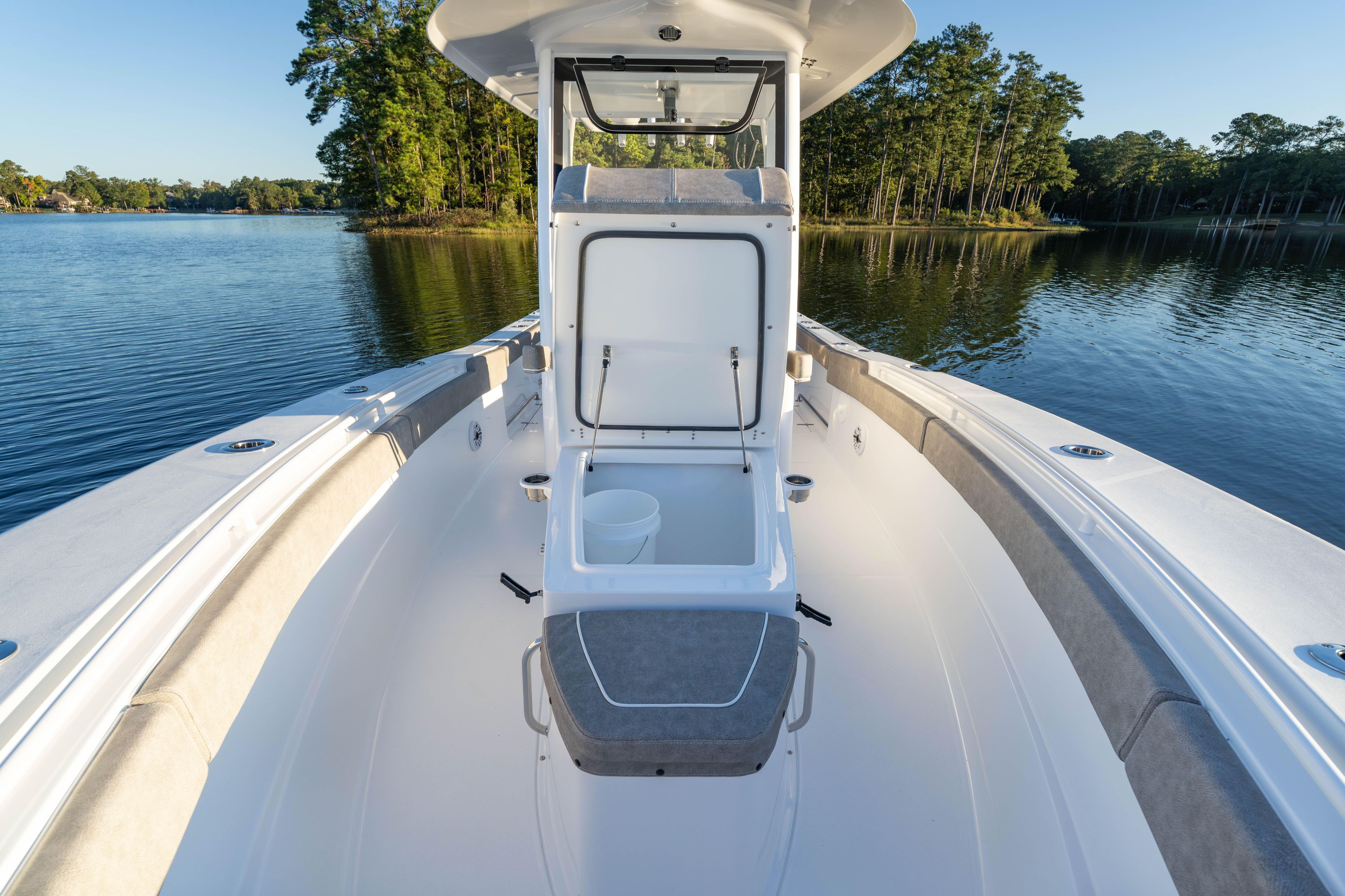 2026 Sea Hunt Ultra 275 Coffin Box boat on serene lake with lush trees.