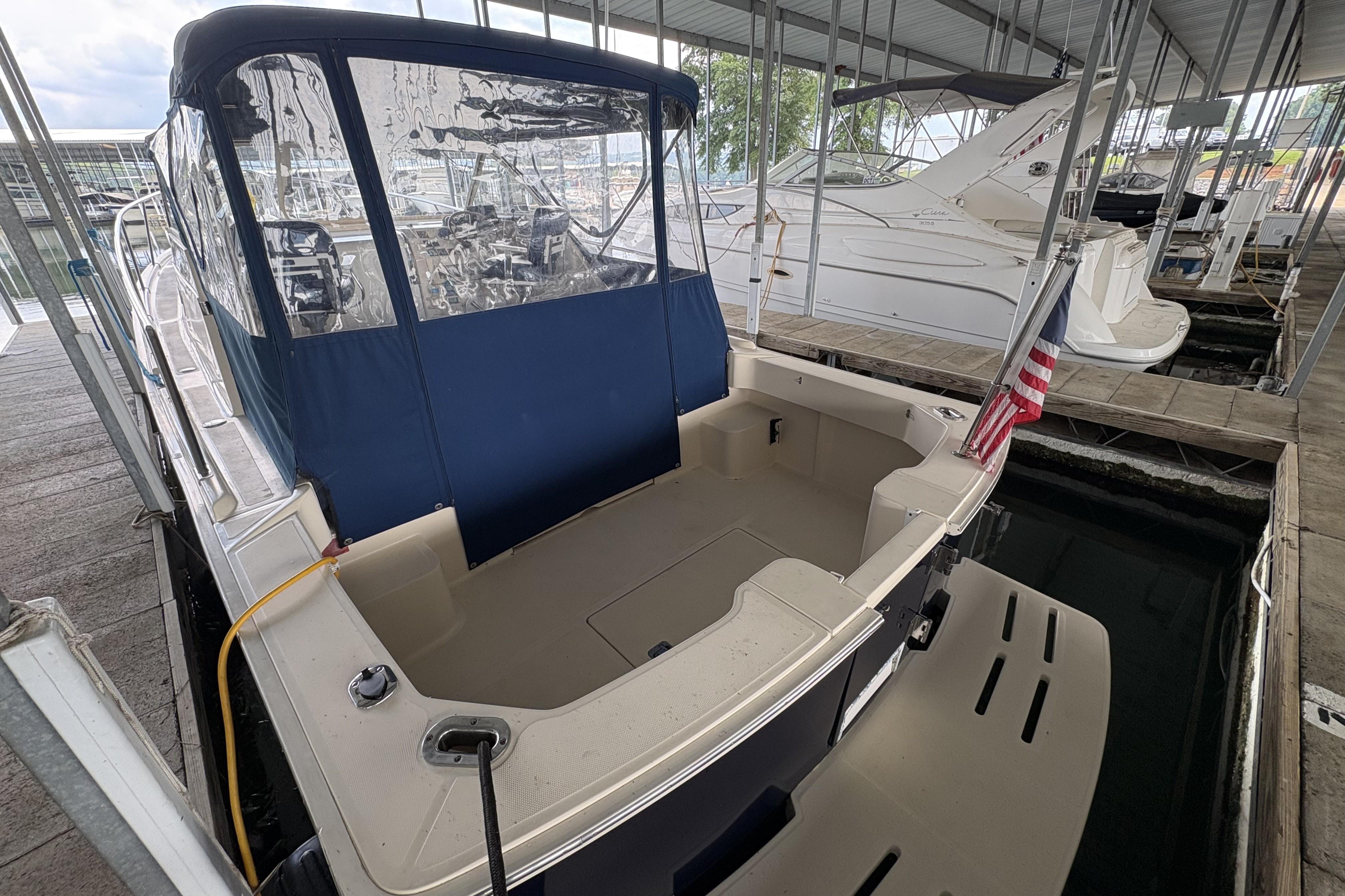2003 Mainship Pilot 30-II docked, featuring a covered cockpit and American flag.
