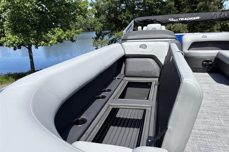 2026 Sun Tracker Party Barge 18 DLX interior with seating and cup holders by a lake.