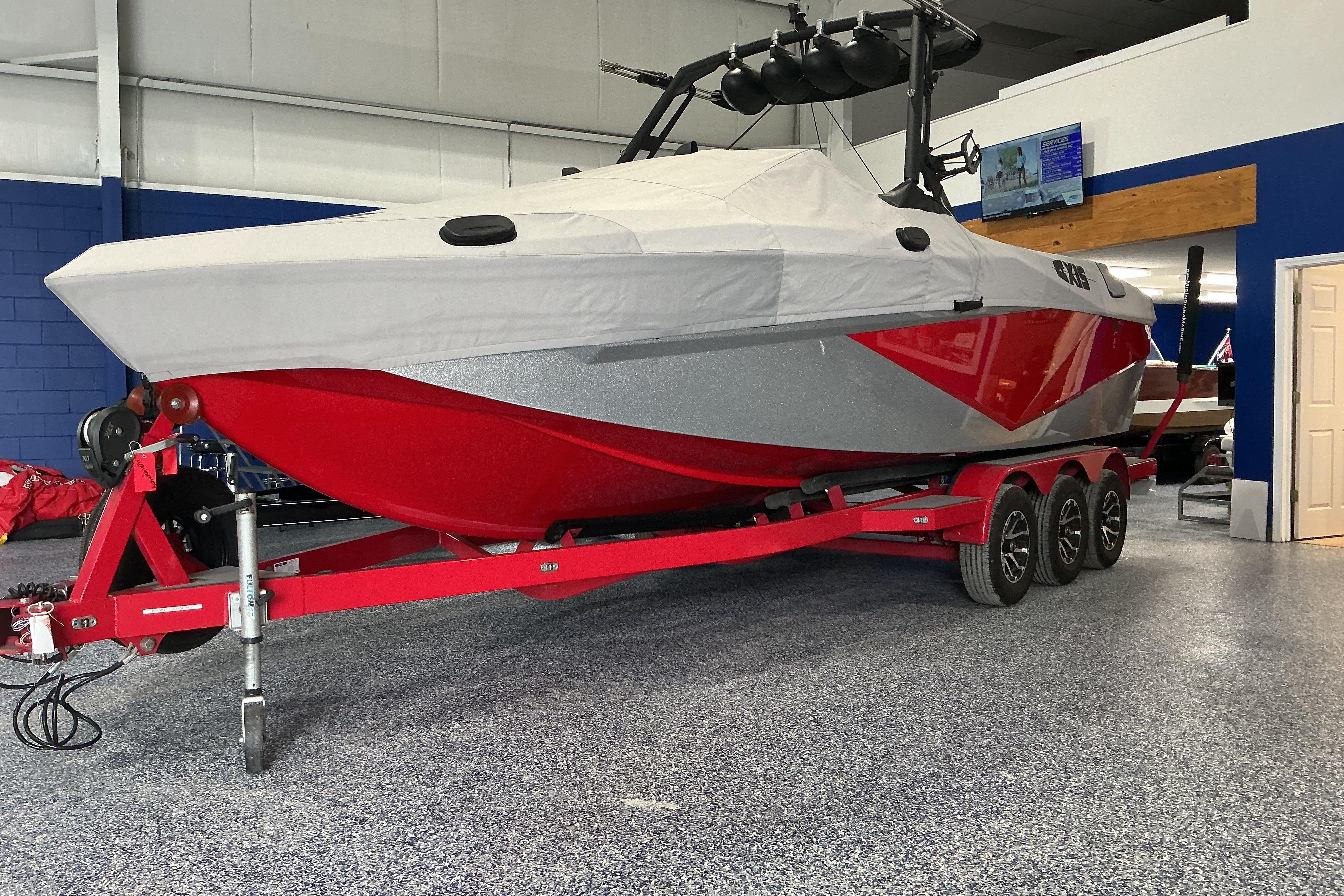 2022 Axis T250 boat with red hull on a triple-axle trailer in showroom.
