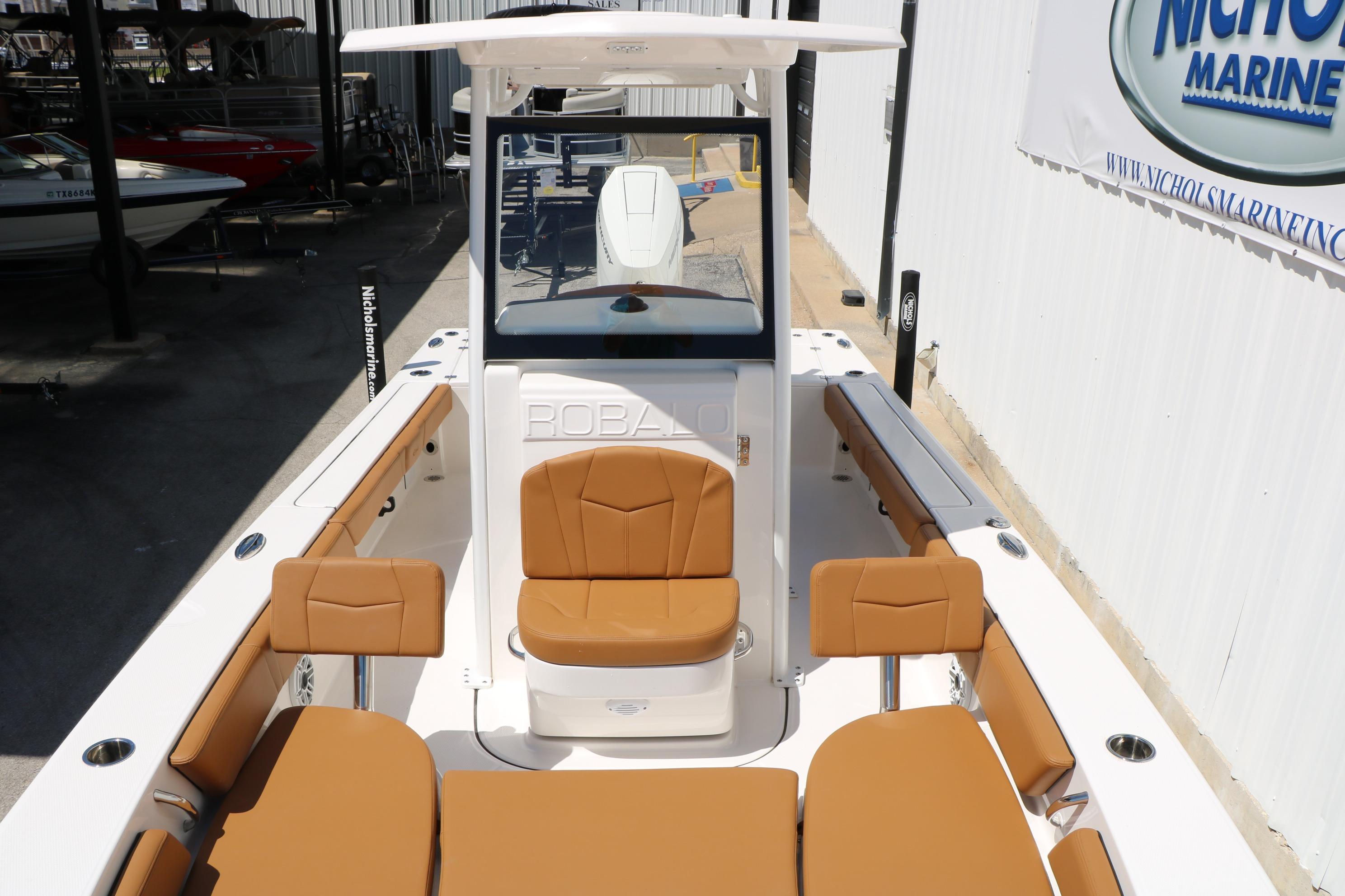 2026 Robalo 246 Cayman boat with tan seating and sleek design in a marina setting.