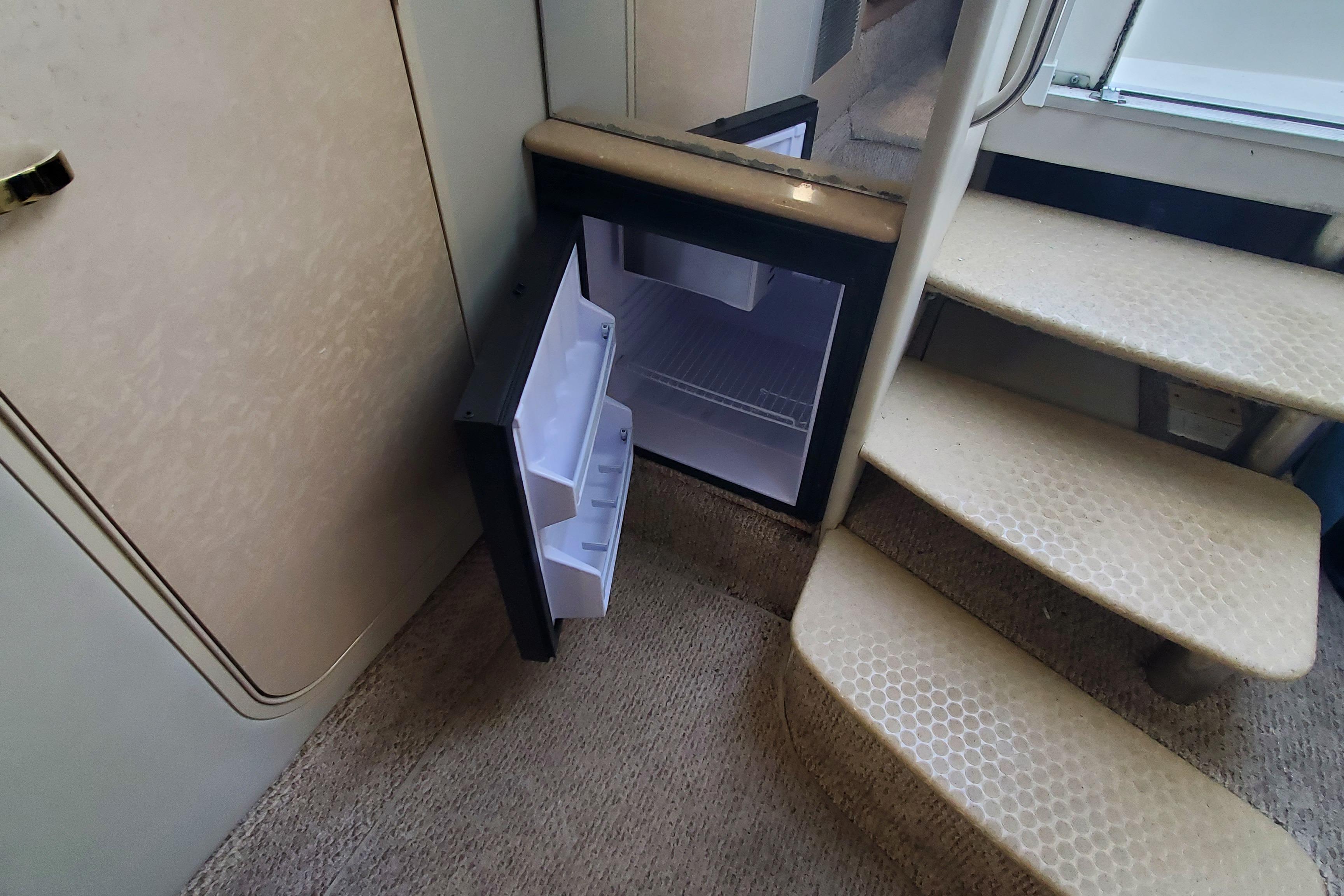 2004 Formula 370 Super Sport interior with open mini fridge and carpeted stairs.