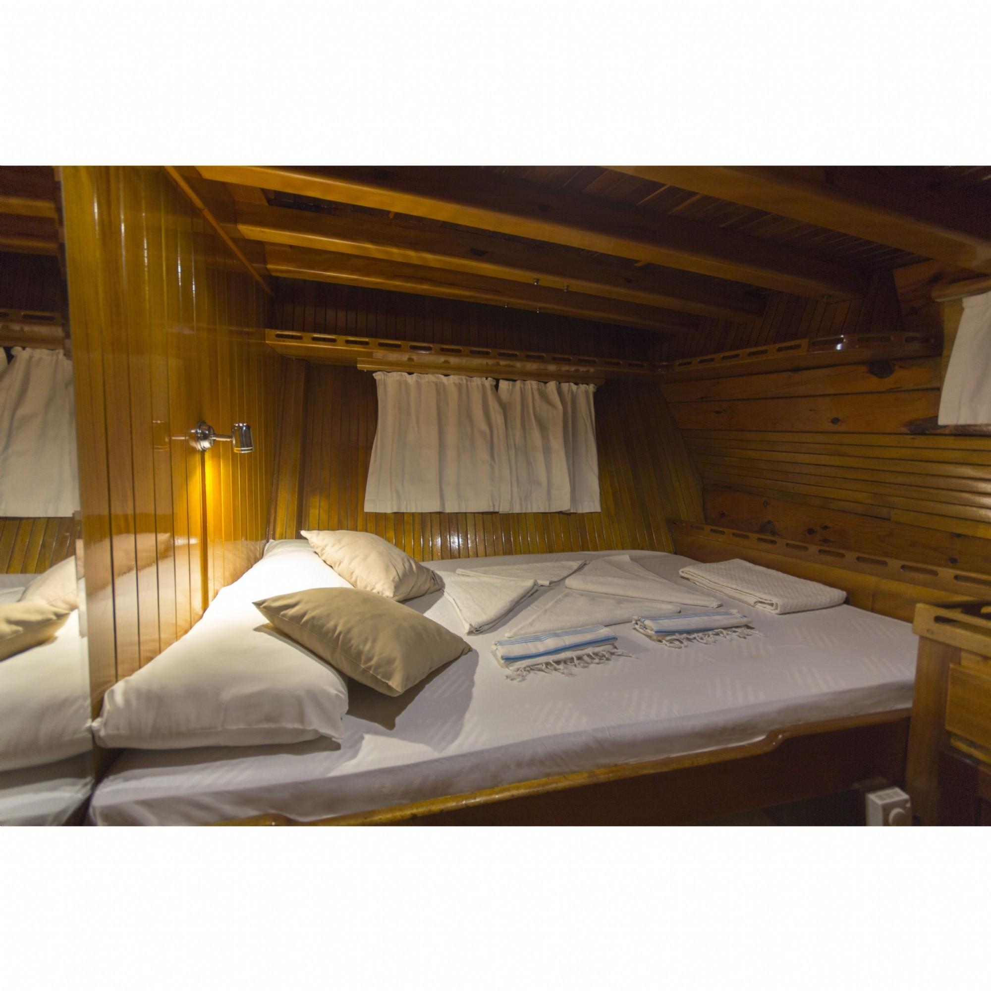 Cozy wooden cabin bedroom with double bed, pillows, and soft lighting, custom-made in 1995.