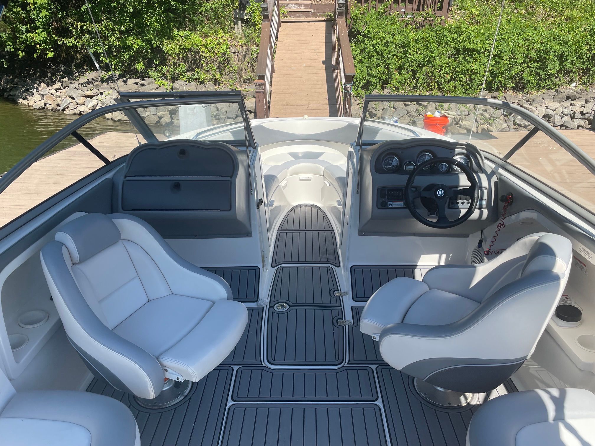 2006 Yamaha SX230 with two white seats and a steering wheel, docked at a wooden pier.