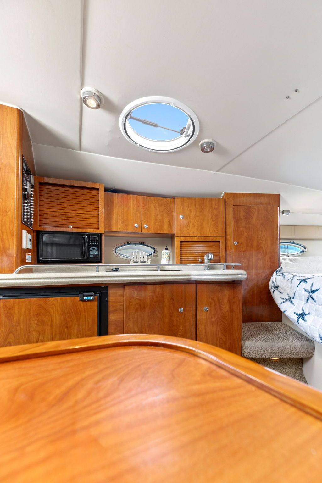 Interior of a 2007 Larson Cabrio 330 with wood cabinetry and a porthole.
