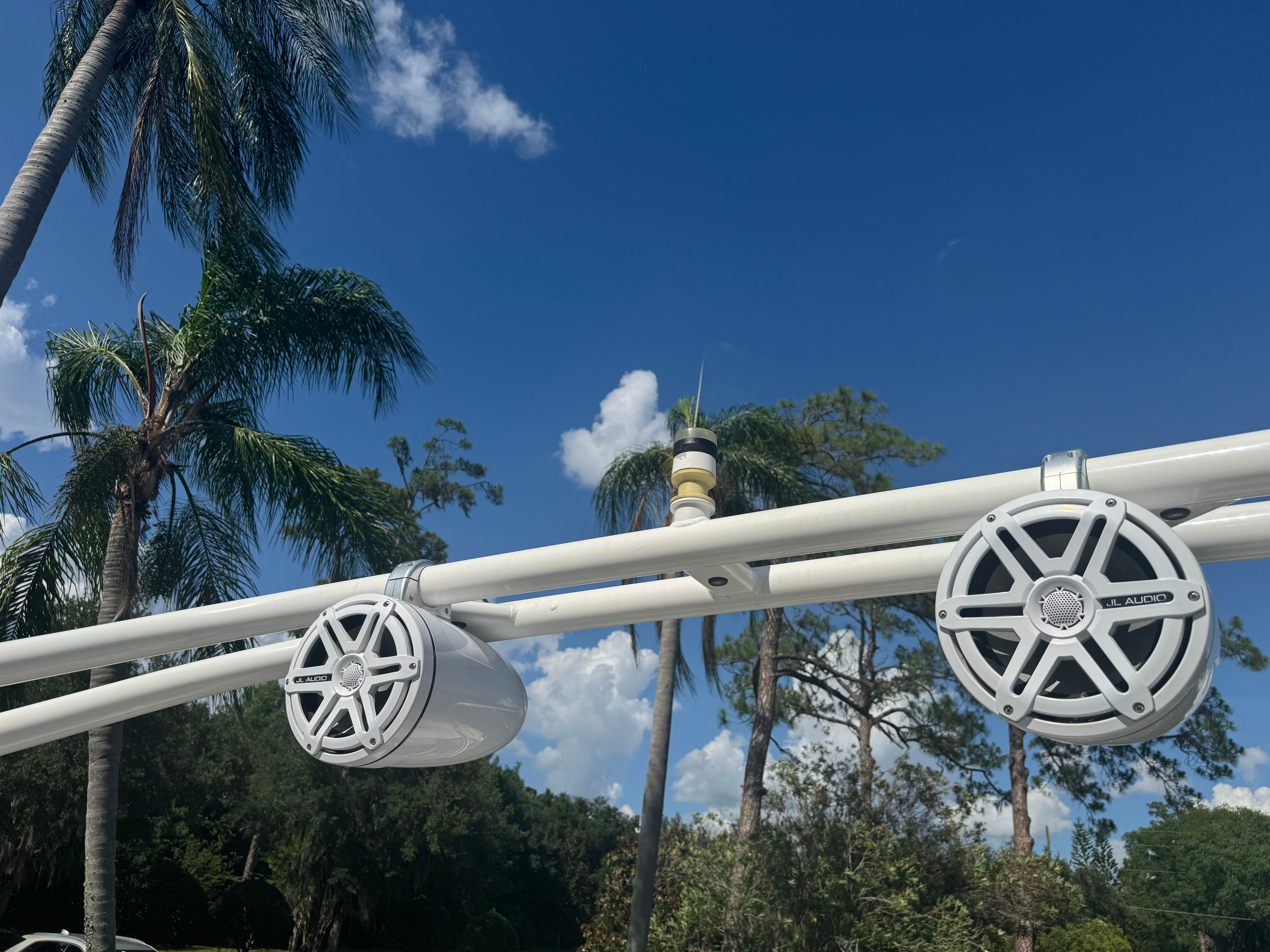 Speakers on a boat with a blue sky and palm trees in the background.