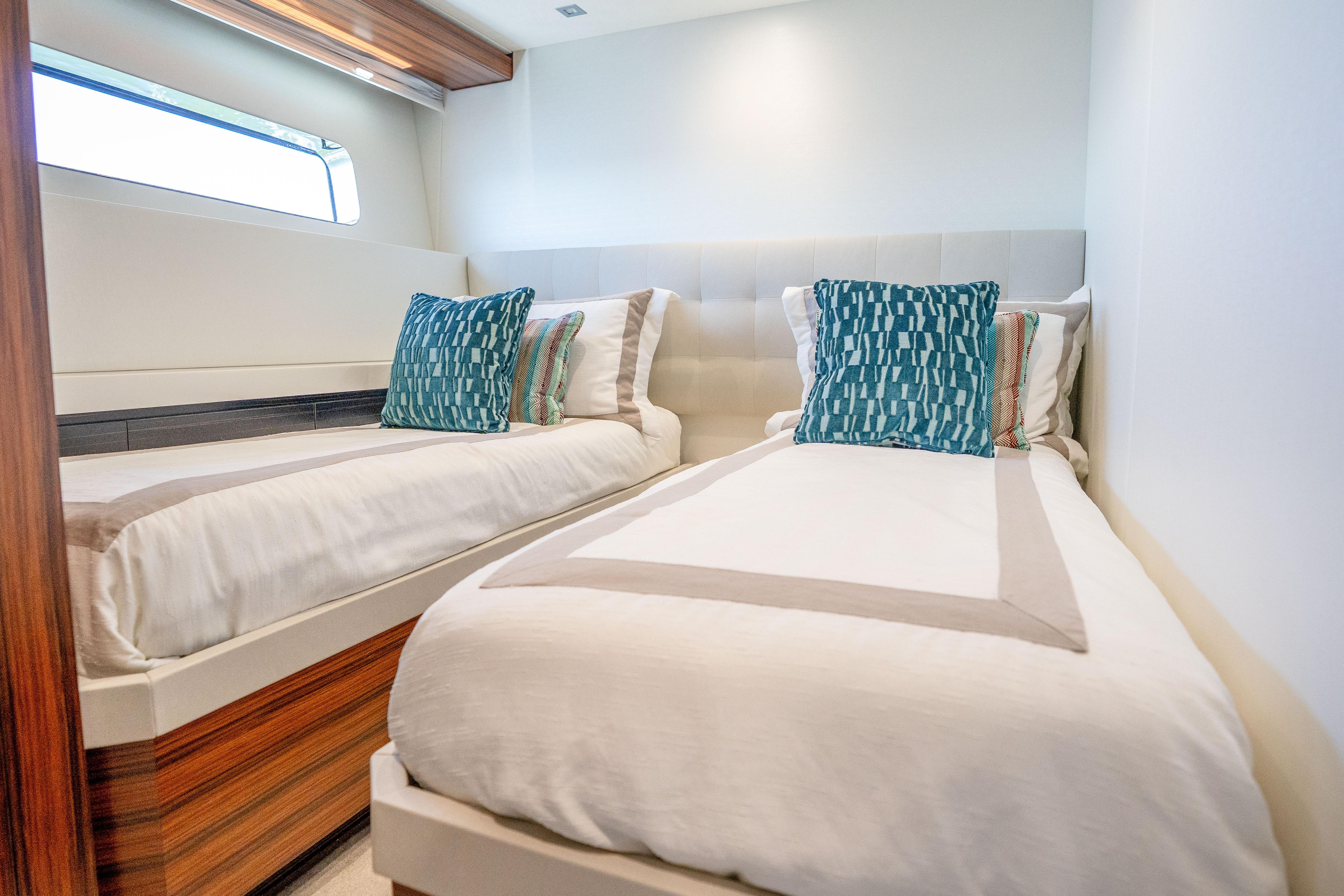 Luxurious twin bedroom on 2021 Hatteras M75 Panacera yacht with modern decor.