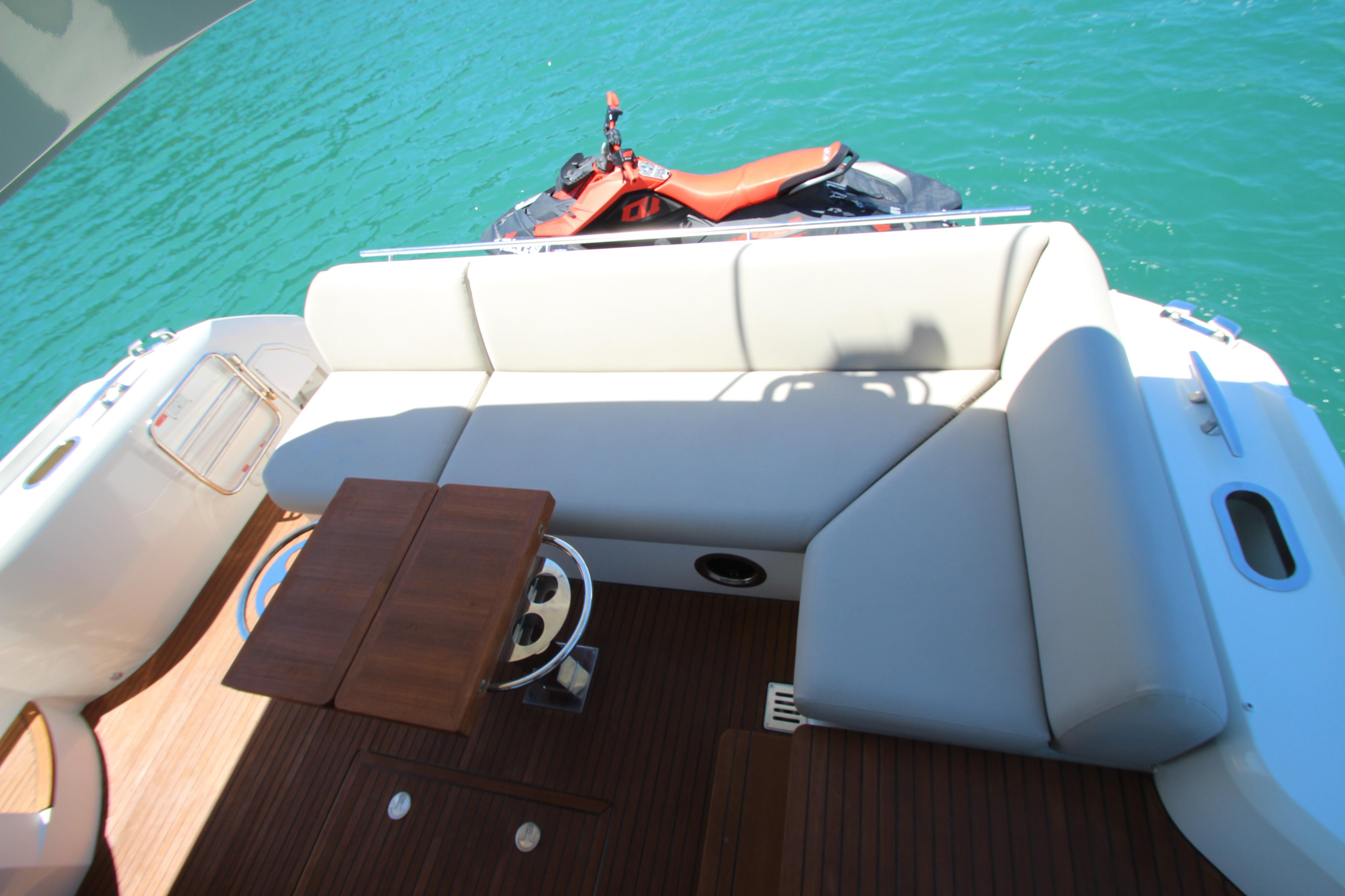 Luxury seating area on 2022 Prestige 520 yacht with jet ski on turquoise water.