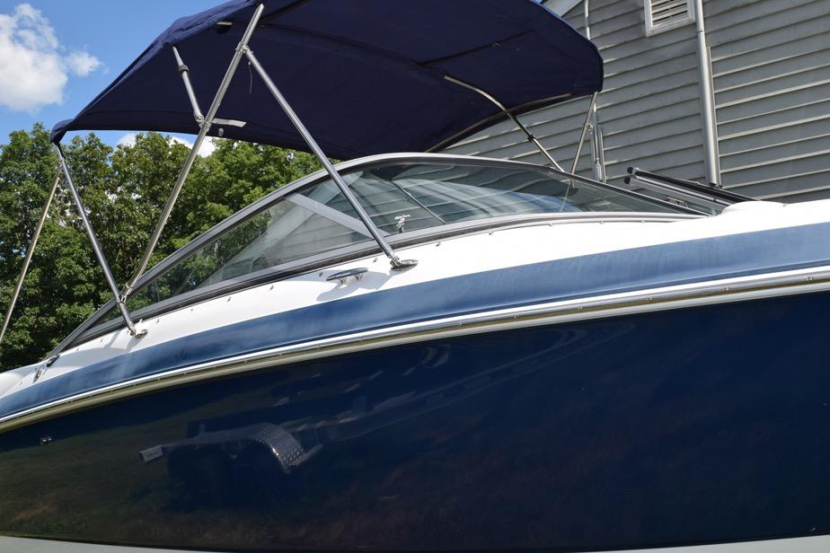 2006 Cobalt 240 boat with blue hull and canopy, parked near a building.