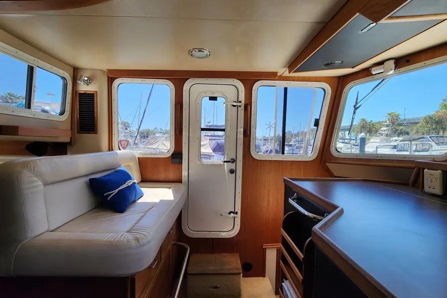 Interior of a 2006 American Tug AT boat, featuring cozy seating and large windows.