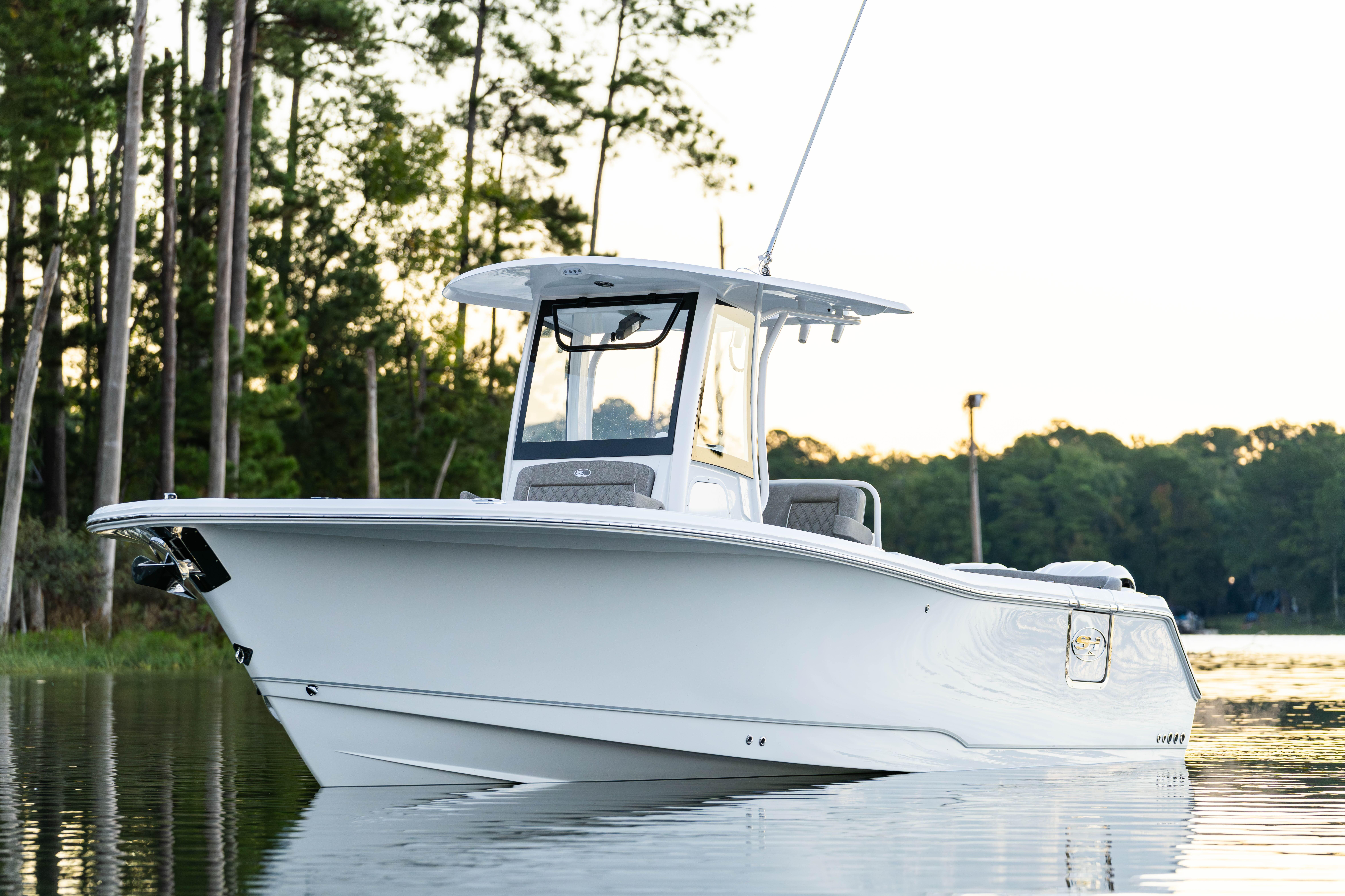 2026 Sea Hunt Ultra 275 Coffin Box boat on calm water, surrounded by trees.