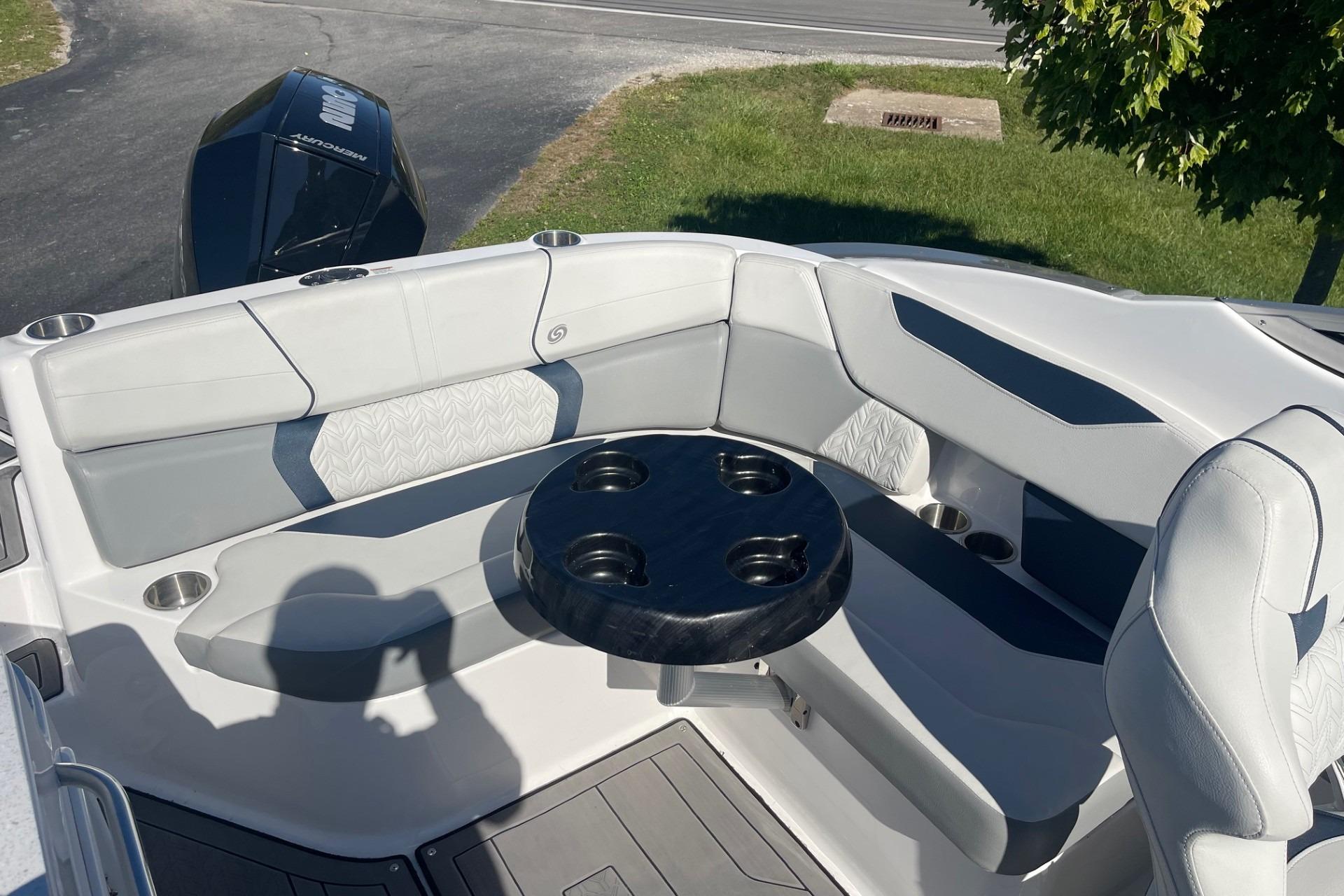 2023 Hurricane SunDeck 2400 OB boat interior with cushioned seating and round table.