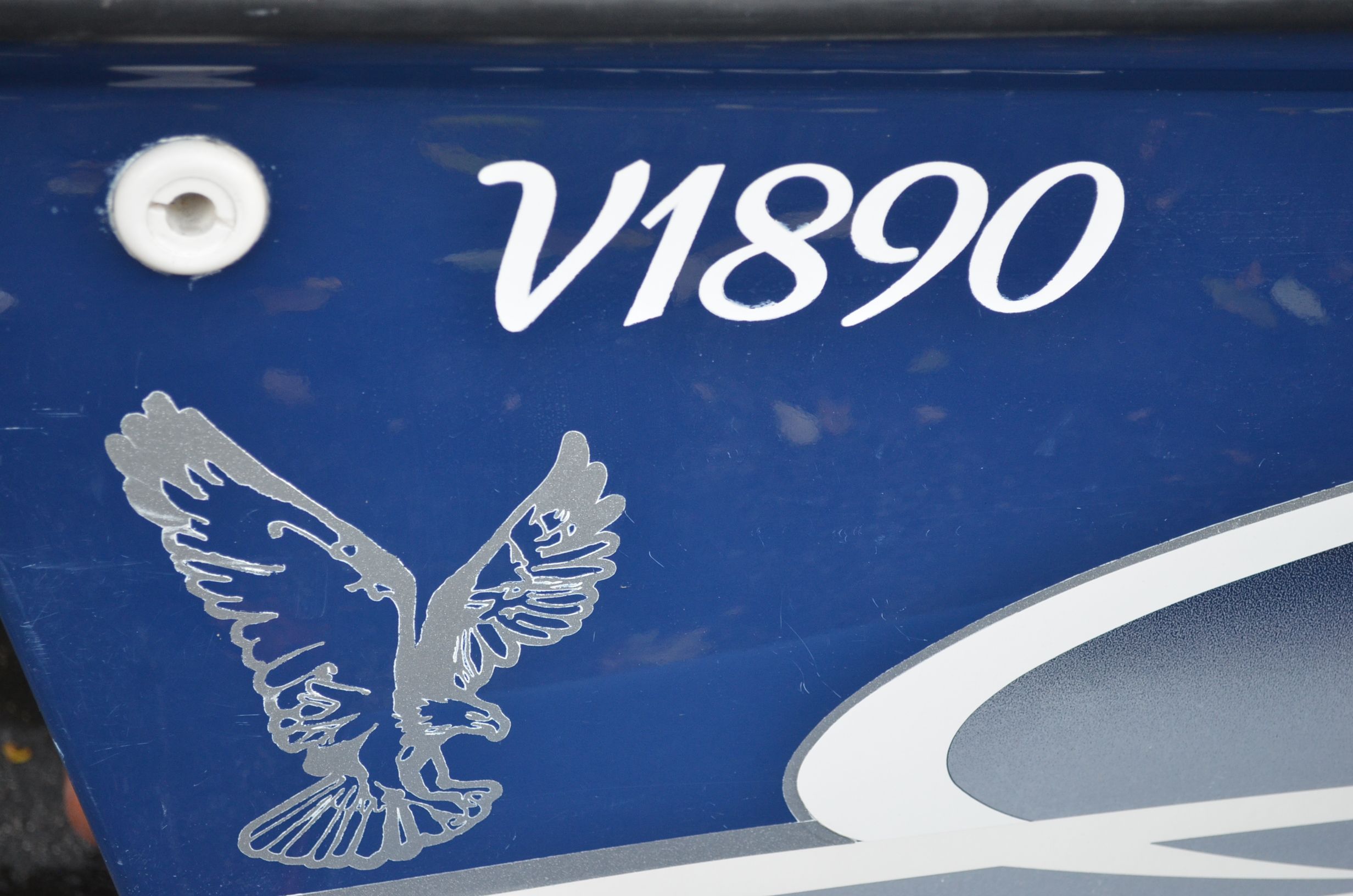 Close-up of blue boat hull with "V1890" and an eagle emblem.