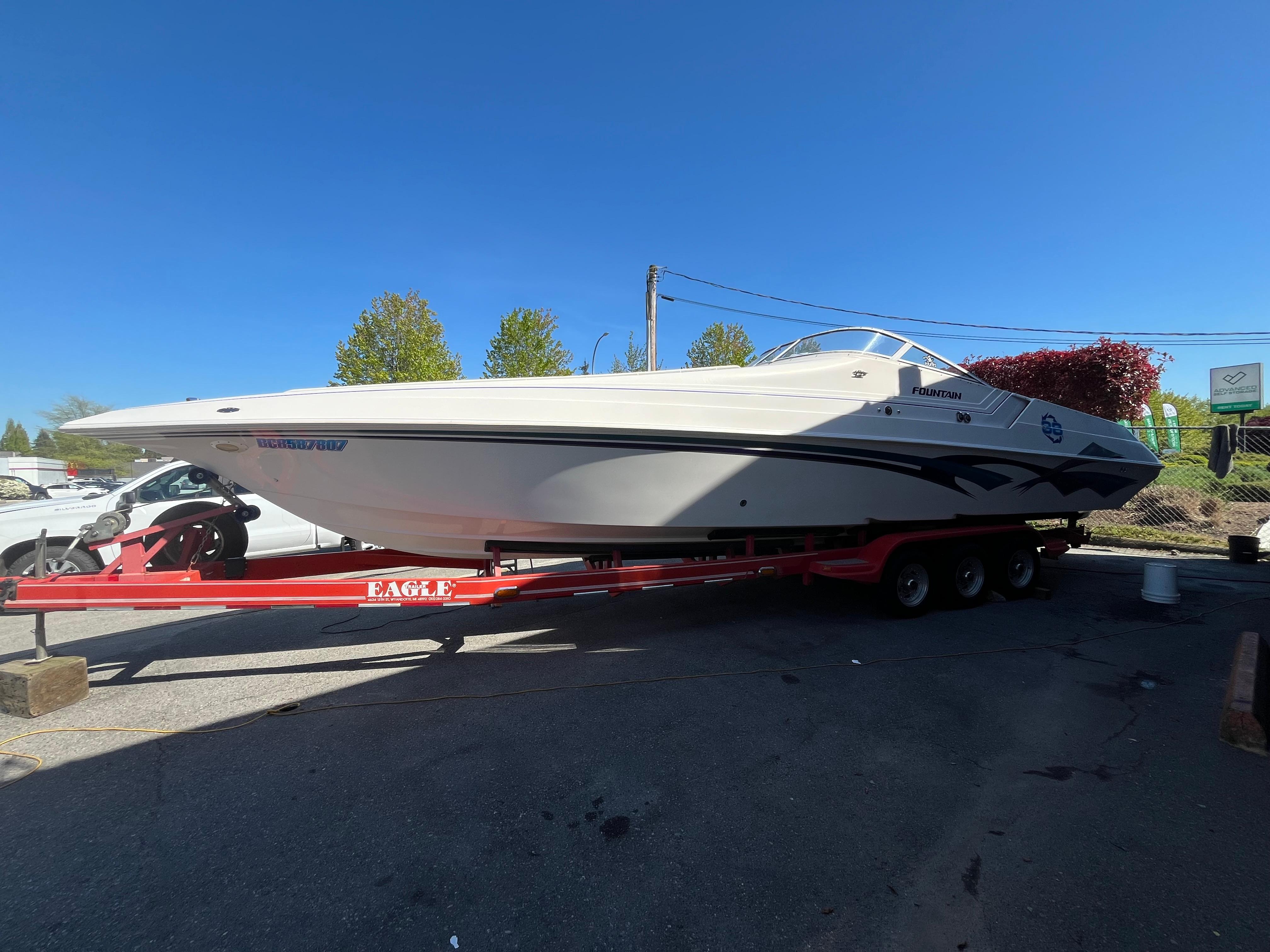 1999 Fountain 38 Sport Cruiser on trailer, parked outdoors under clear blue sky.