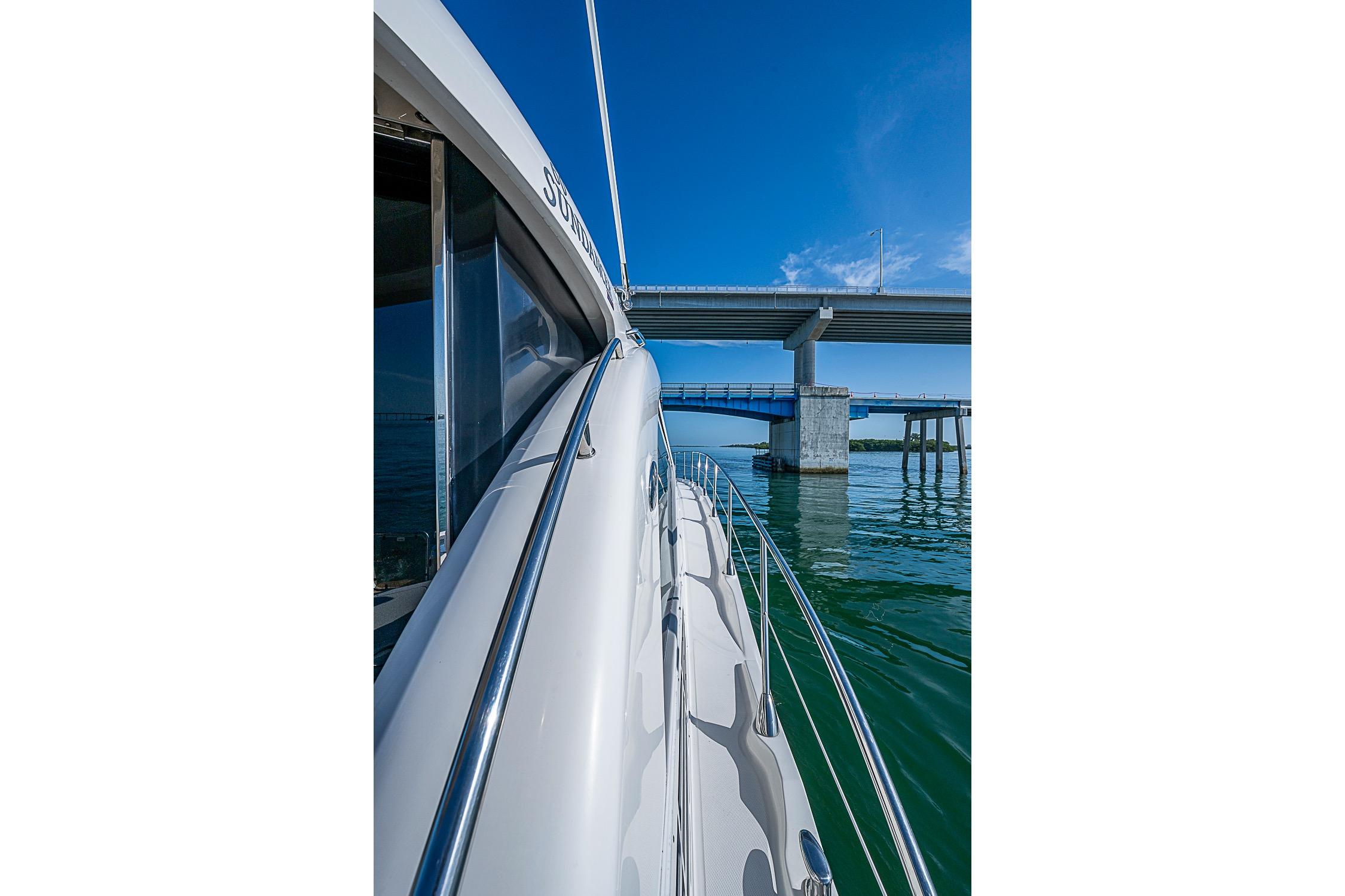 2008 Sea Ray 60 Sundancer yacht cruising under a bridge on a sunny day.