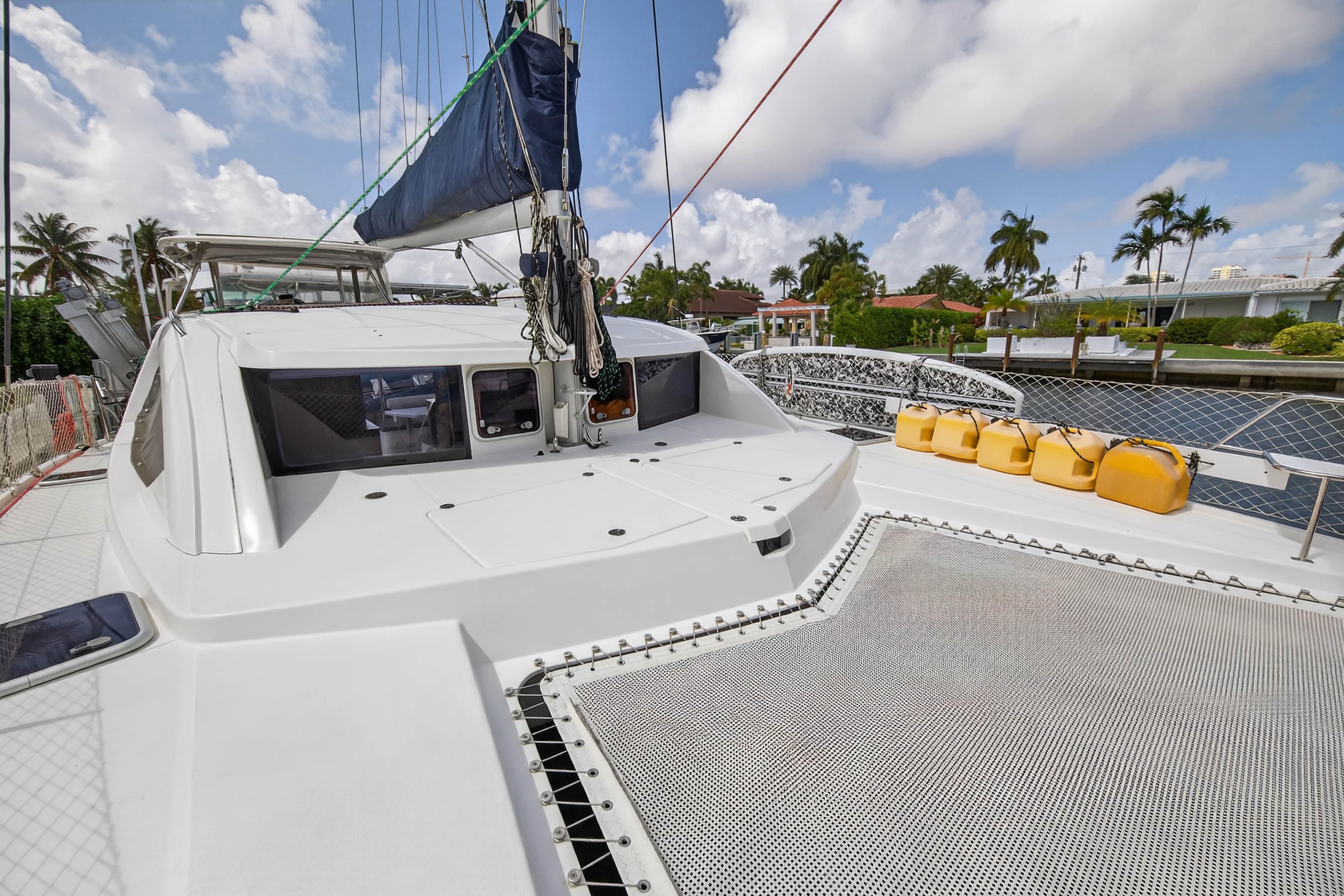 2012 Leopard 39 catamaran deck with netting and yellow fuel containers, docked by palm trees.