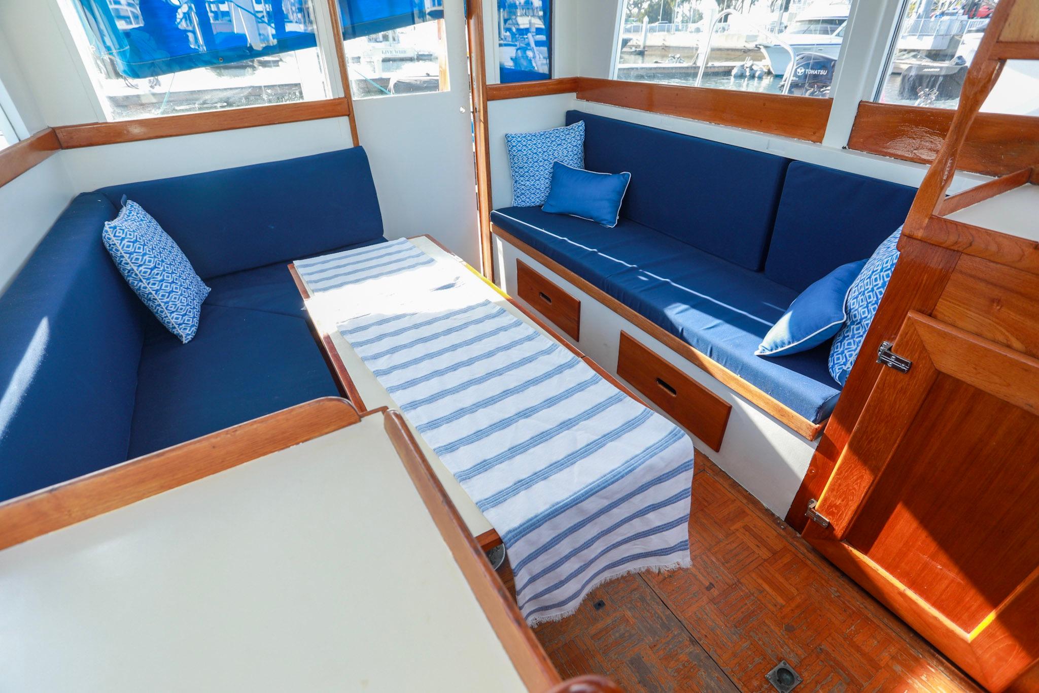 Interior of 1973 Grand Banks 32 Sedan with blue seating and striped tablecloth.