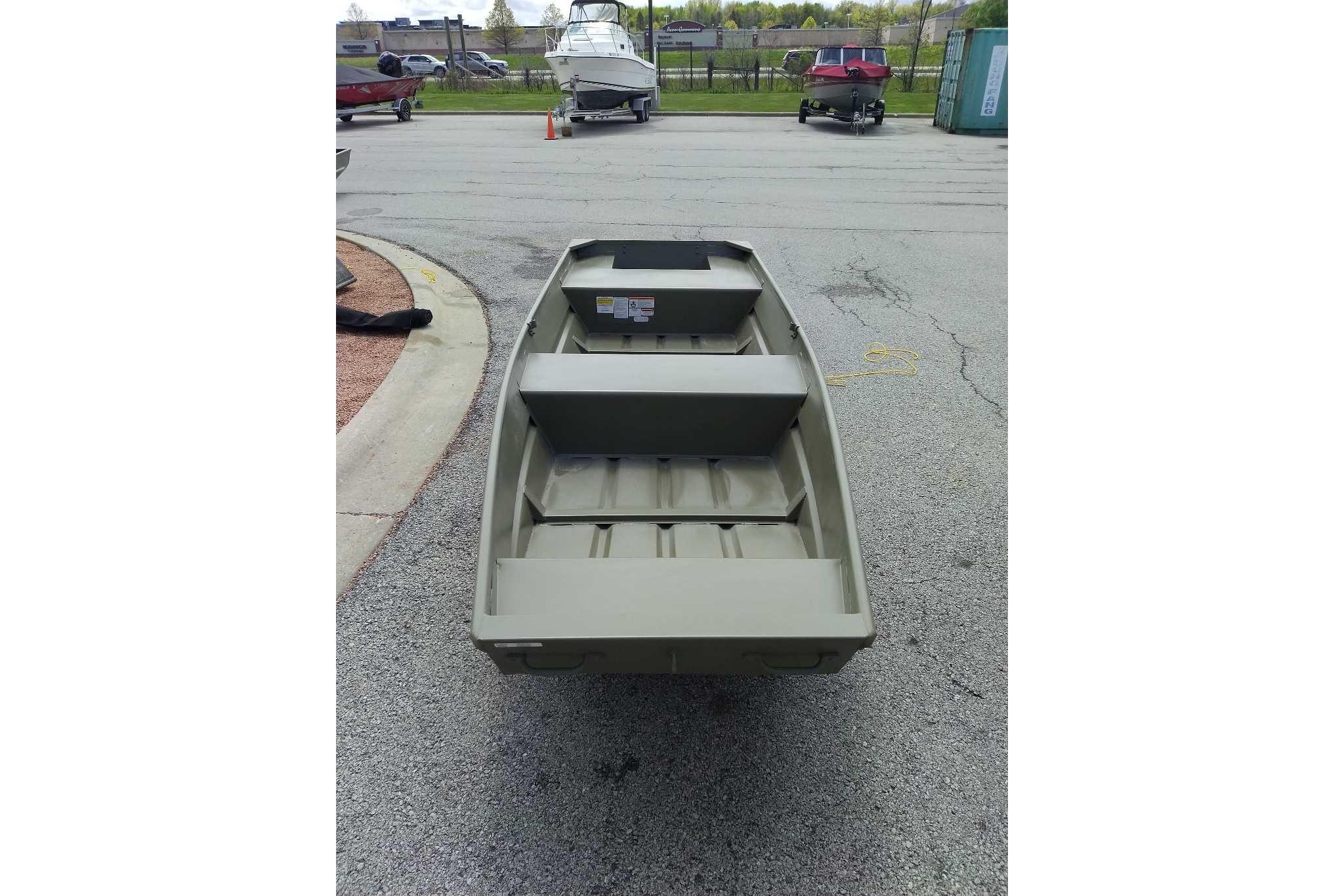 2026 Tracker Grizzly 14 Jon boat on pavement, showcasing interior seating and storage.
