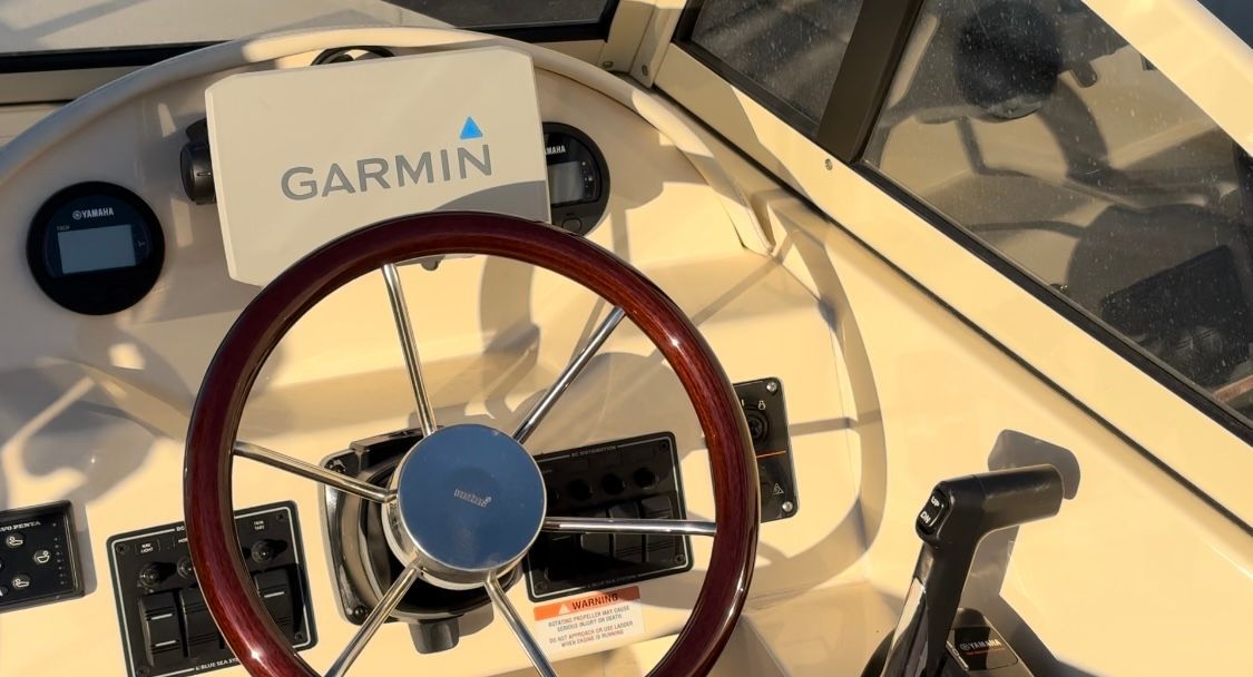 Helm of a 2018 Rossiter Coastal Cruiser with Garmin navigation system and wooden steering wheel.