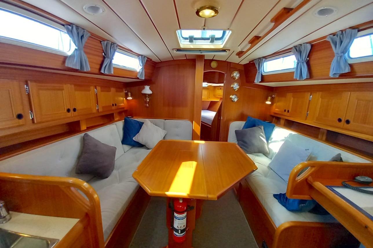 Interior of 1994 Najad 370 yacht with wooden furnishings and cozy seating area.