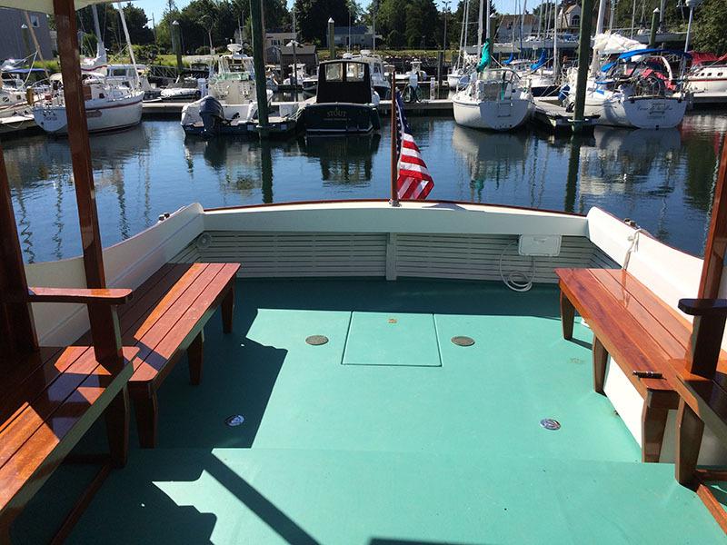 Classic Cruiser 1934 Hemingway's Pilar Replica docked, featuring wooden benches and American flag.