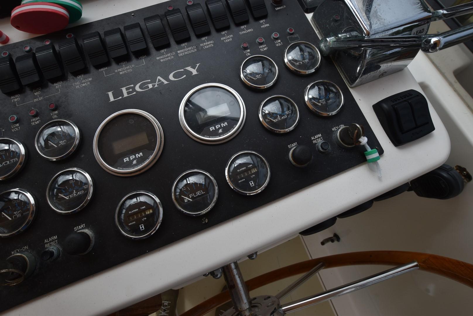 Control panel of a 1999 Legacy 34 Express boat with gauges and switches.