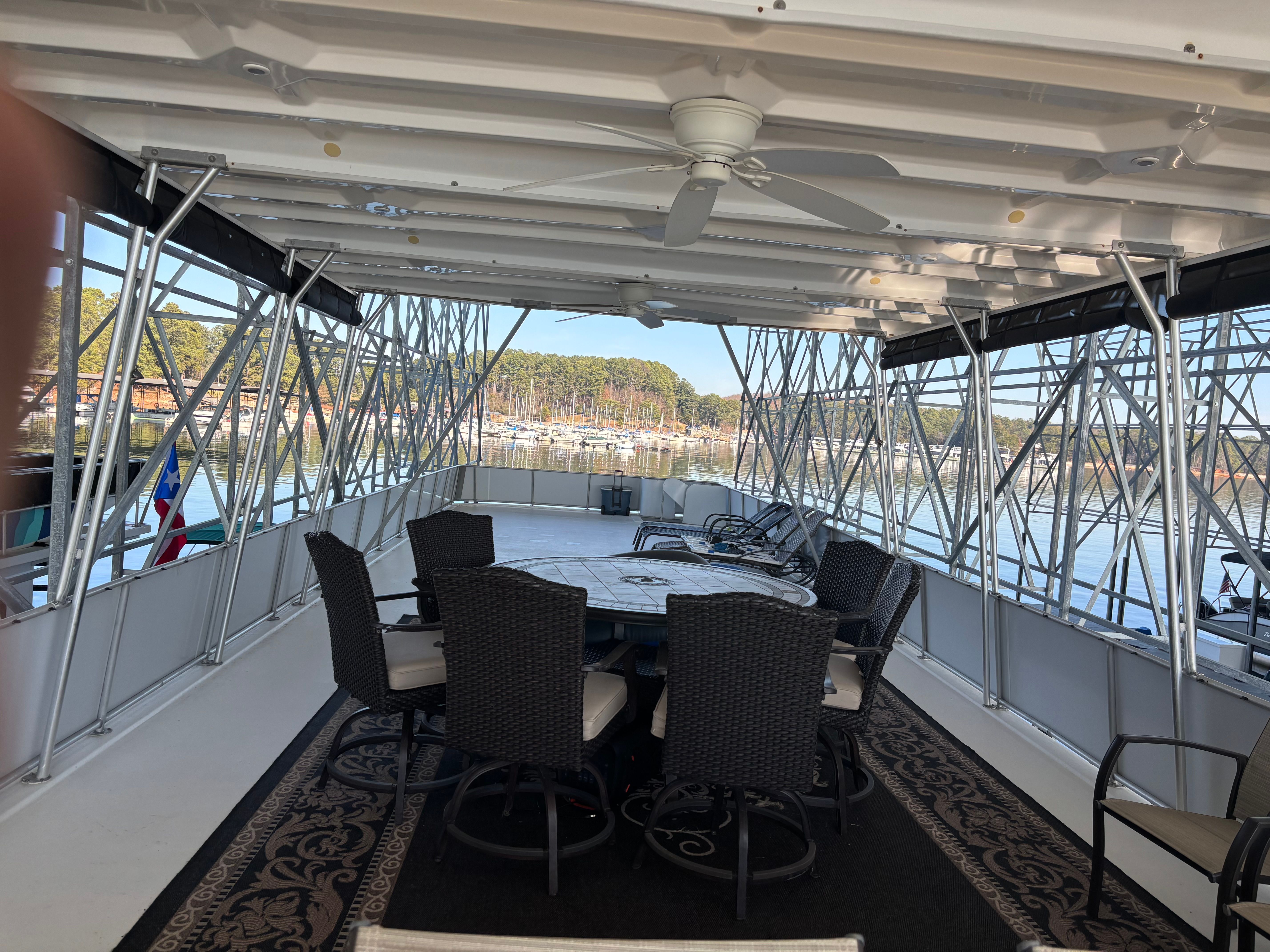 The image shows a houseboat deck with table and chairs, surrounded by water.