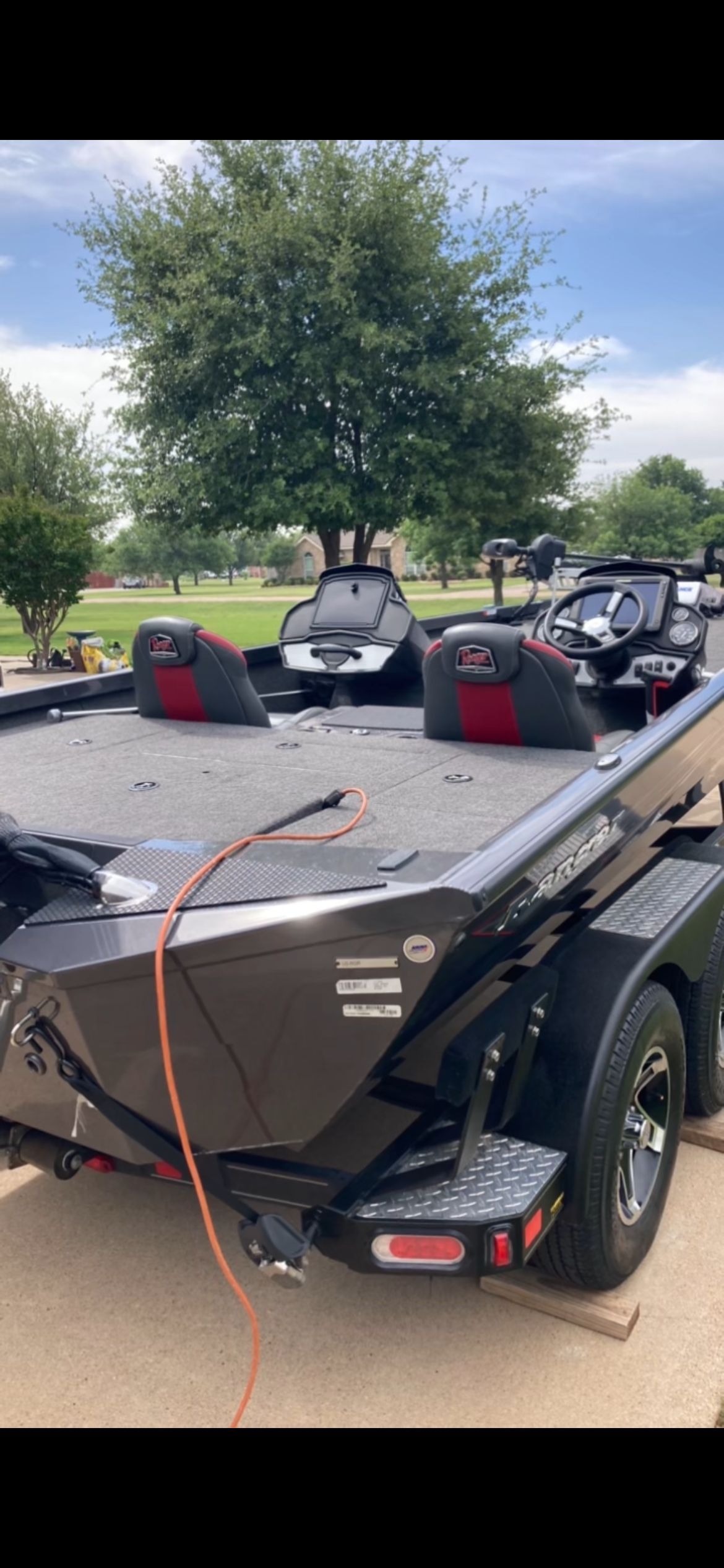 A 2020 Ranger R T 198 p boat on a trailer, surrounded by trees and grass.
