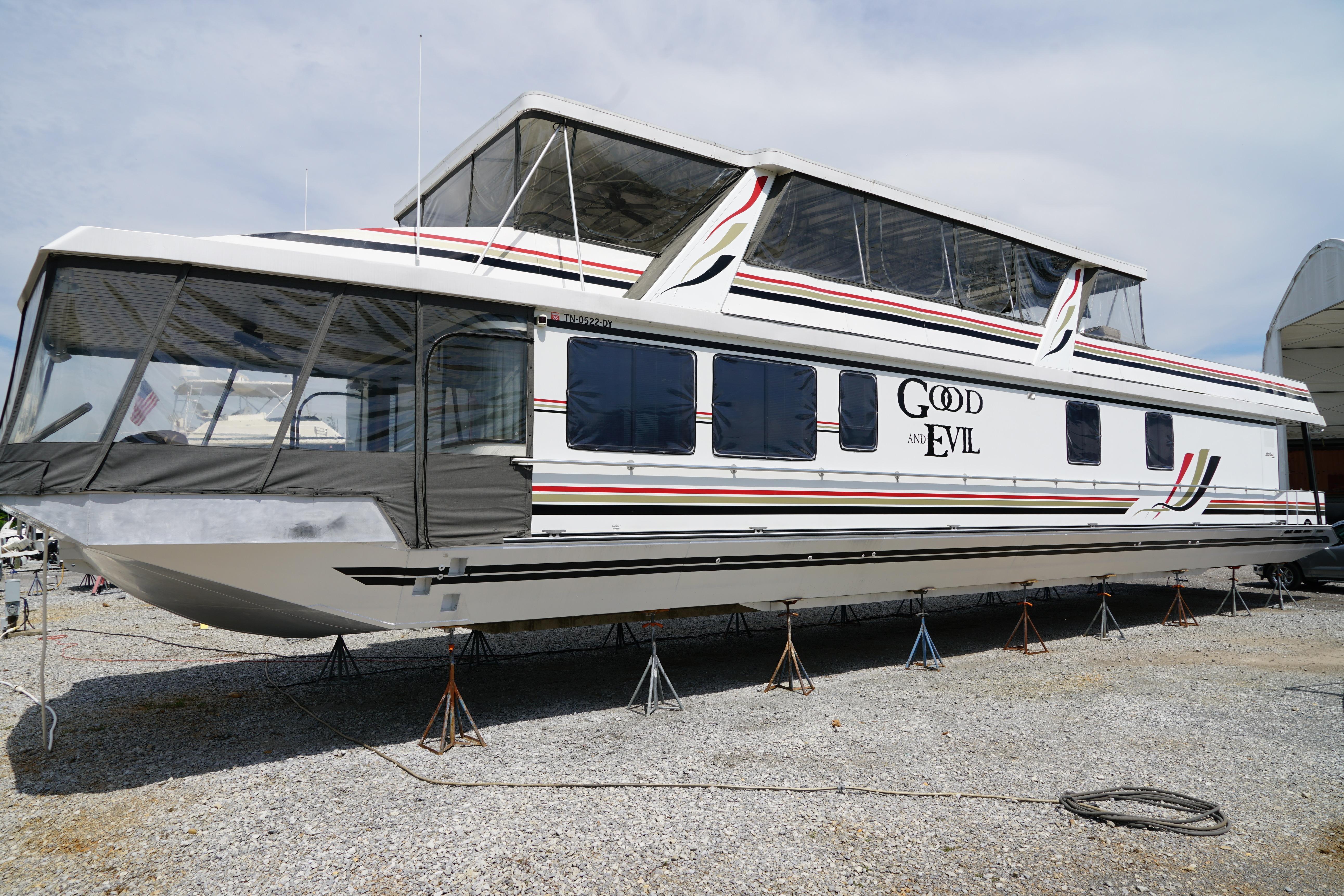 A large houseboat by Stardust Cruisers, model 83'x17', year 2000, is on a dry dock.