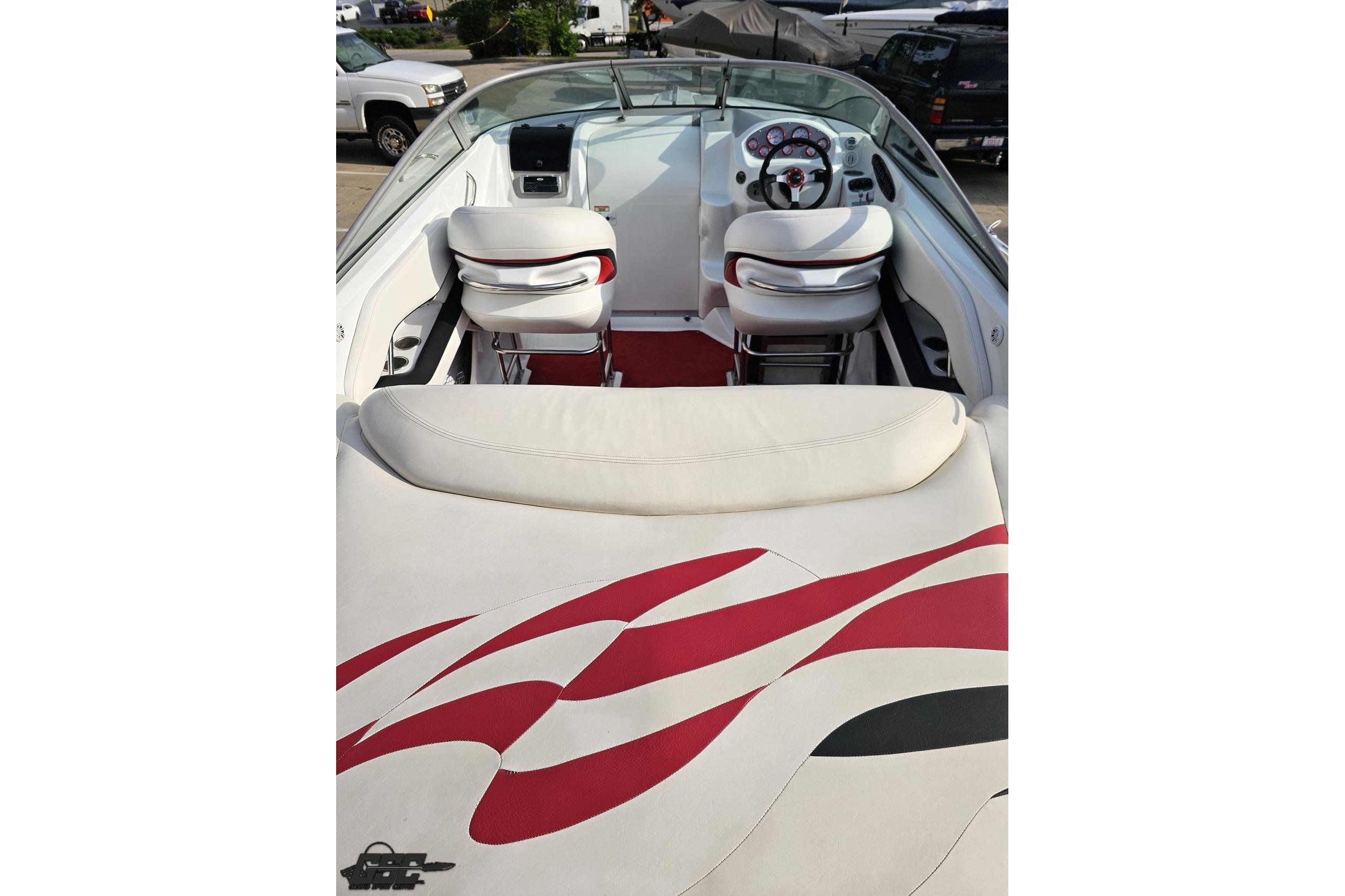 2004 Baja 275 boat interior with white and red seating, steering wheel, and dashboard.