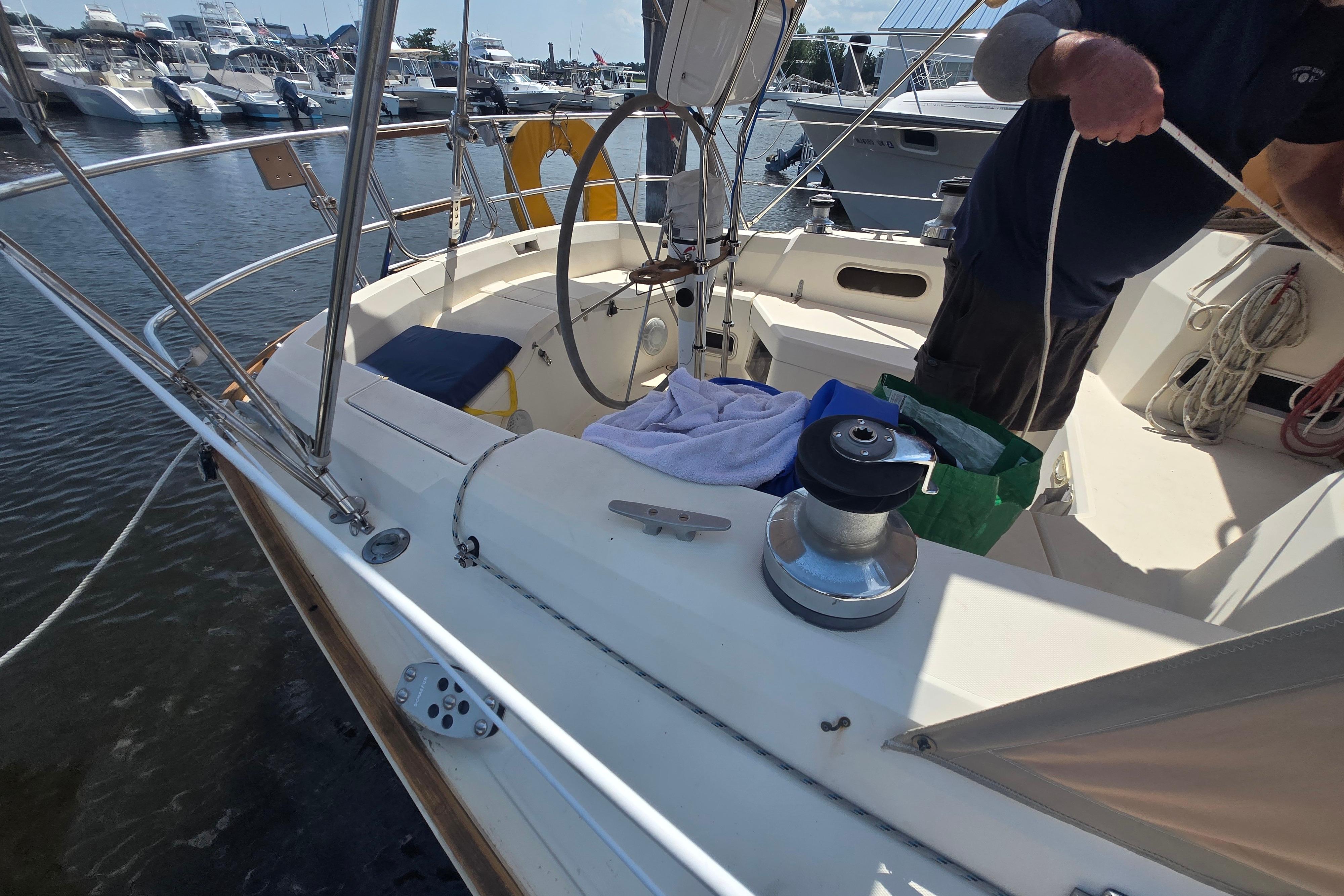 Cockpit of a 1988 Sabre 38 sailboat docked at a marina, featuring steering wheel and winch.