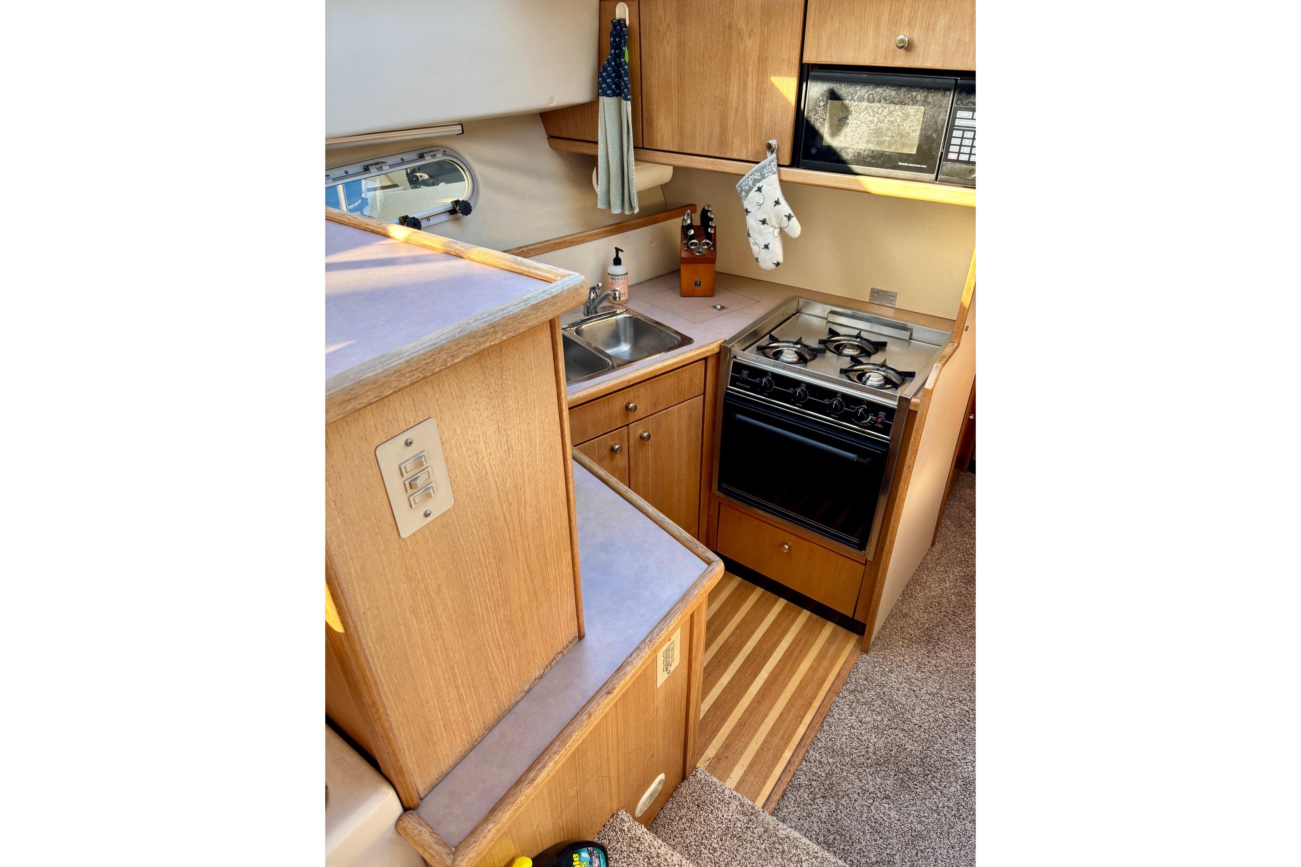 1998 Bayliner 3388 Command Bridge Motoryacht kitchen with stove, sink, and microwave.