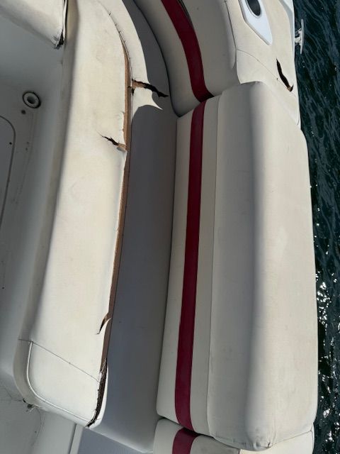 Close-up of worn upholstery on a boat seat with red stripes.
