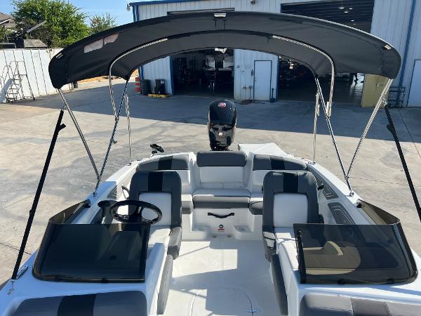 2024 Tahoe T21 boat with canopy and seating, parked outside a warehouse.