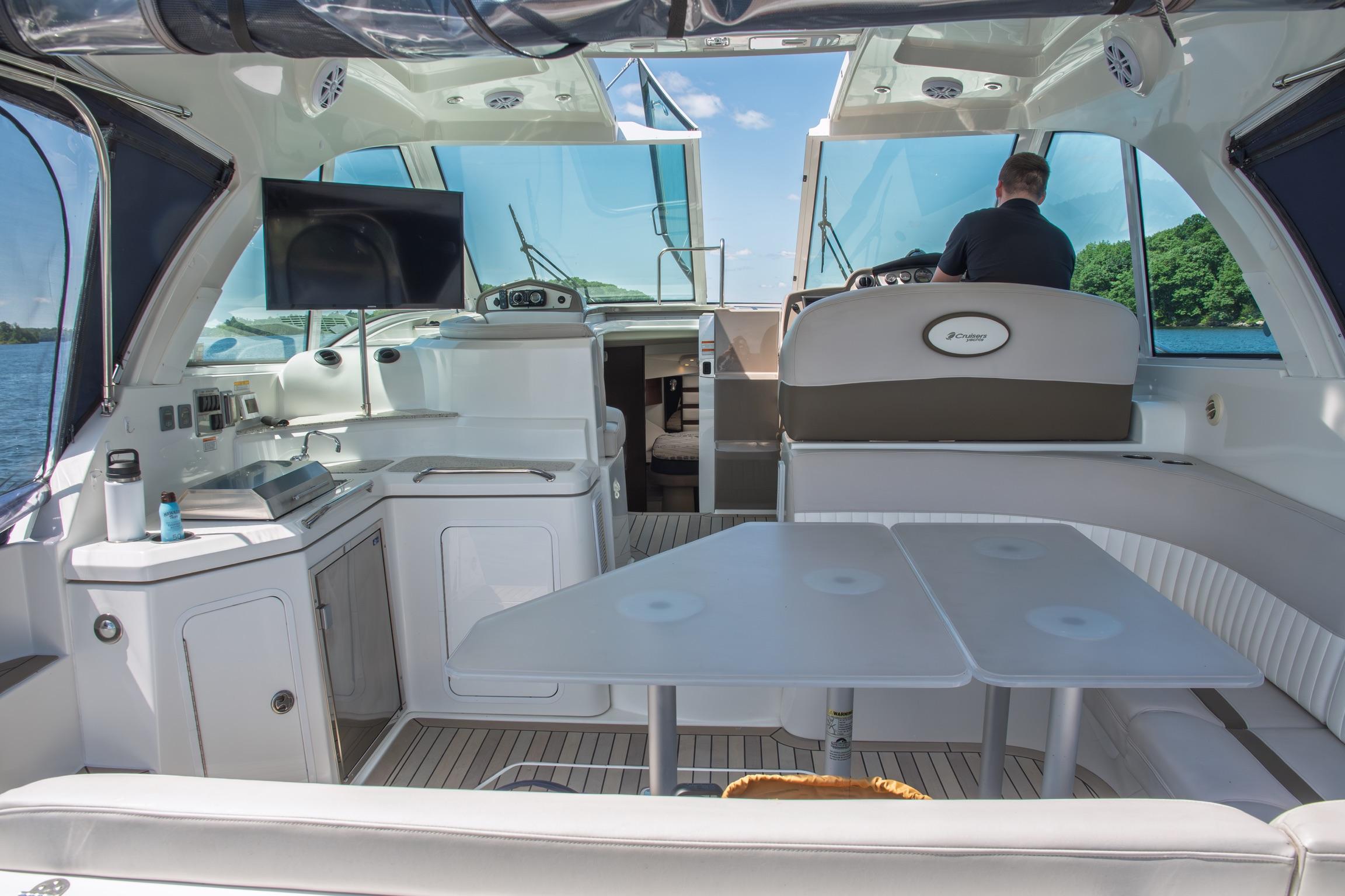 2011 Cruisers Yachts 420 Sport Coupe interior with helm, seating, and kitchenette on a sunny day.