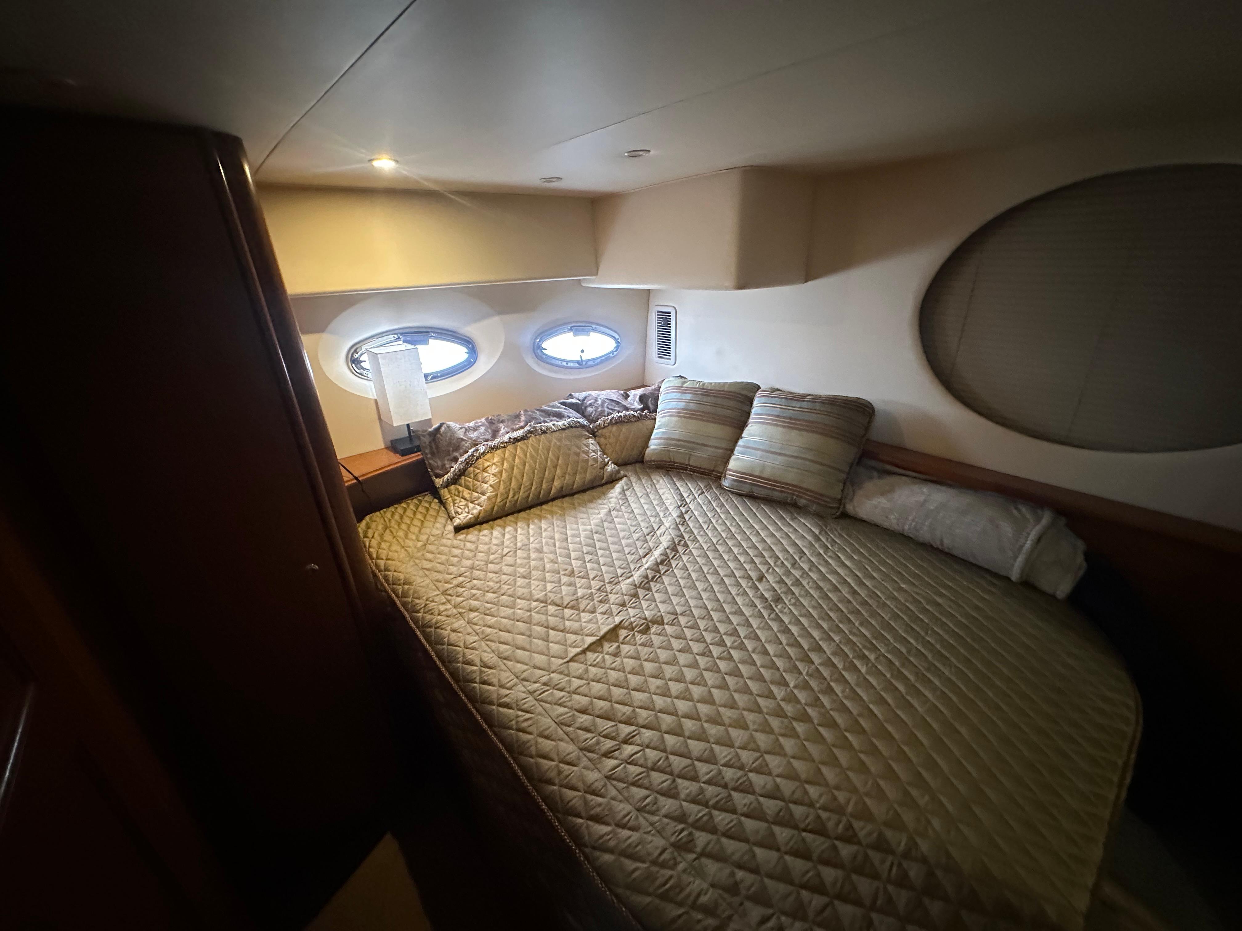 2008 Silverton 35 Motor Yacht bedroom with cozy bed, pillows, and porthole windows.