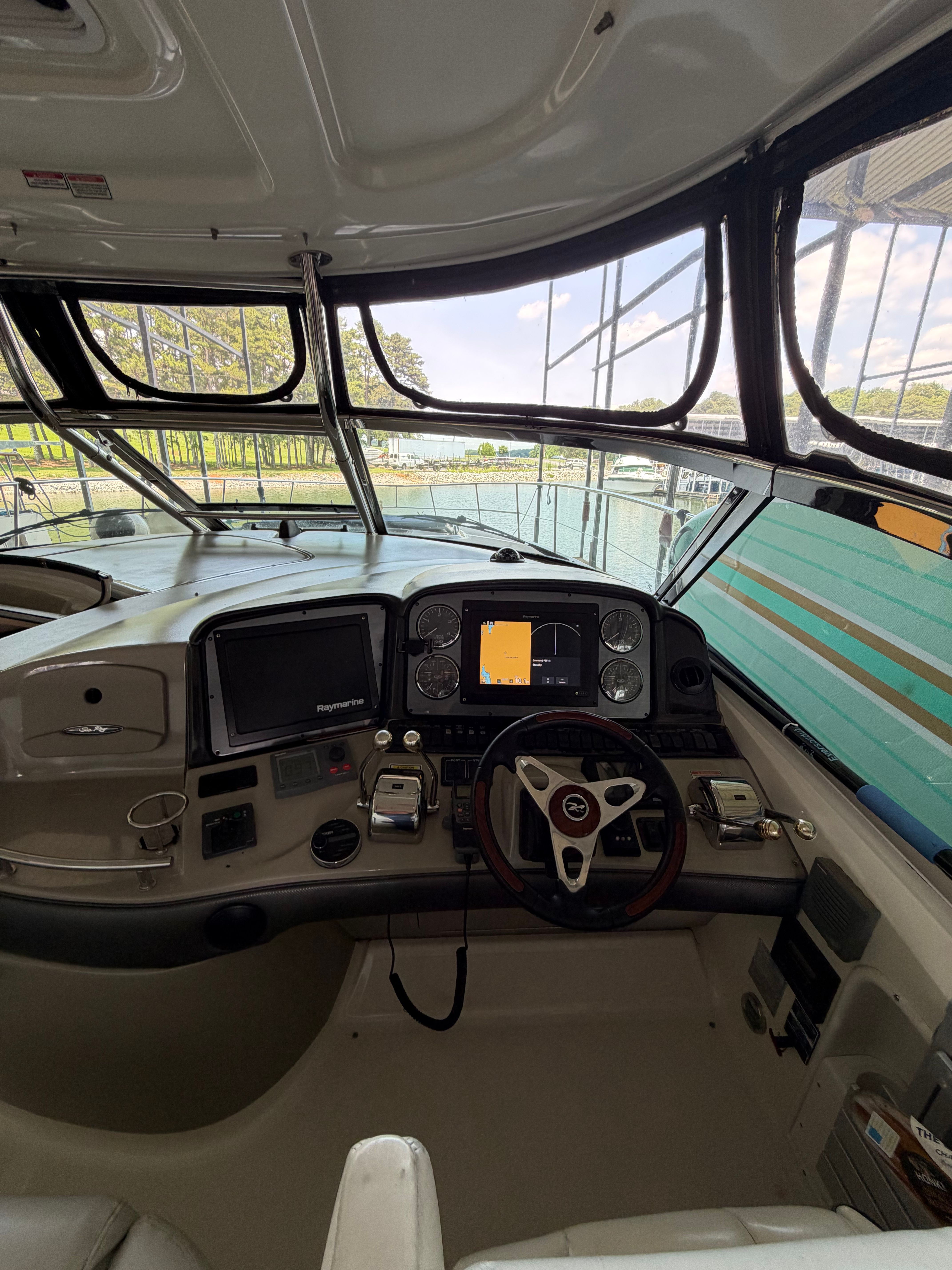 The cockpit of a 2005 Sea Ray 420DA with steering wheel, instruments, and screens.