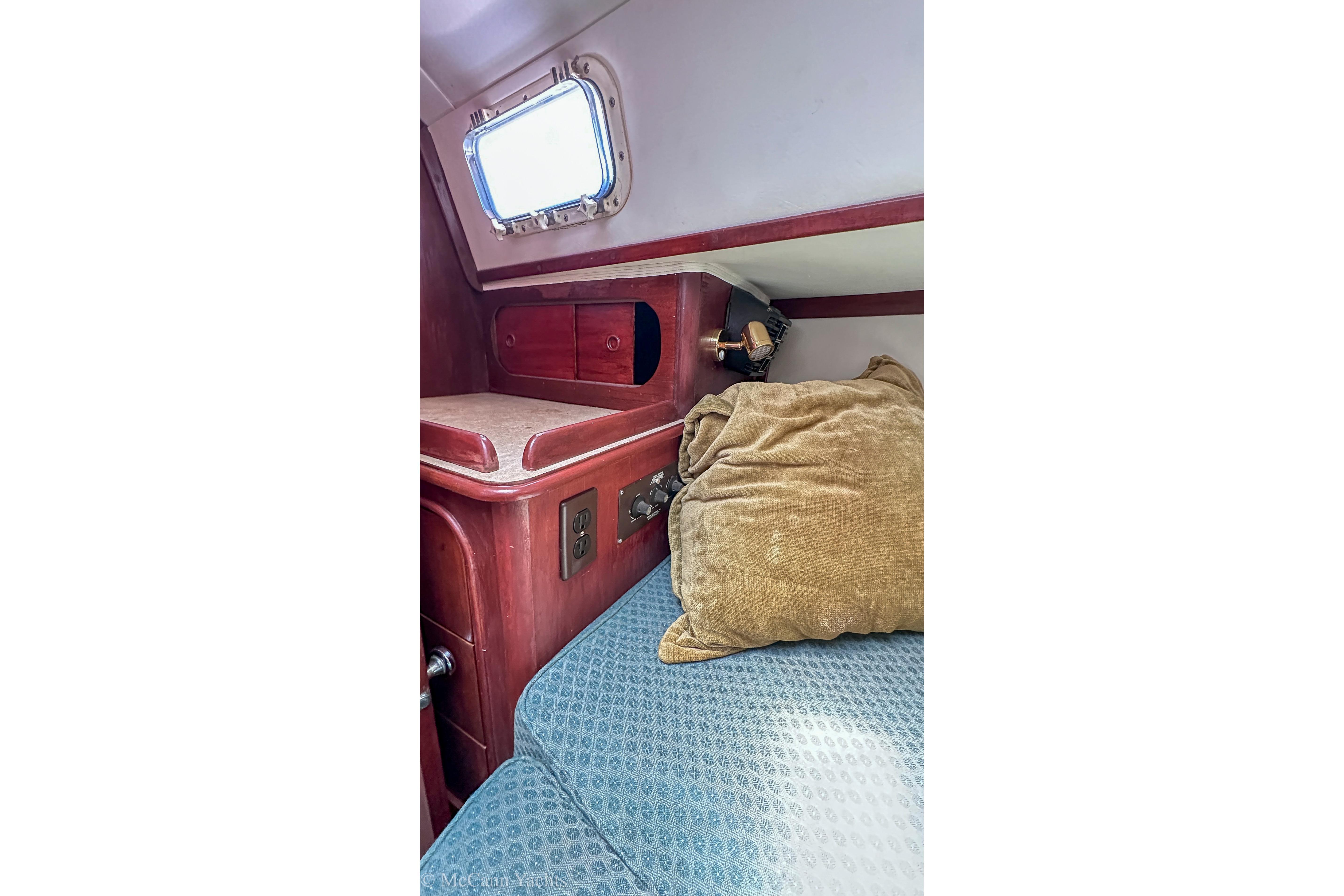 Cozy cabin interior of 1980 Irwin 46 sailboat with wooden accents and porthole.