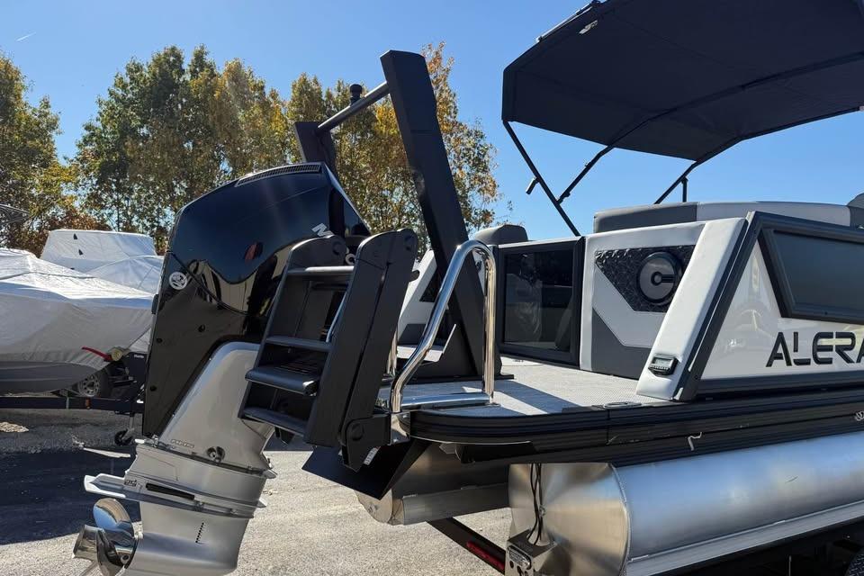 Alera M 25Q 2026 pontoon boat with outboard motor and canopy, parked outdoors.
