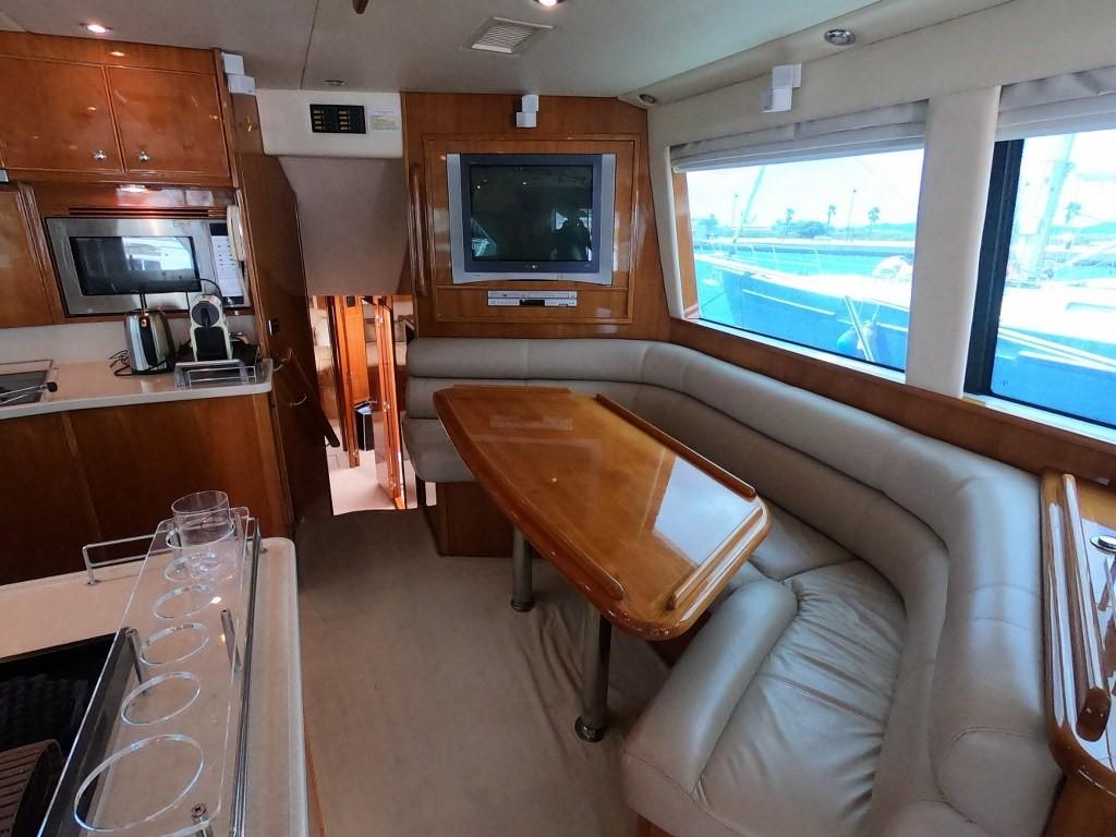 Luxurious interior of 2003 Riviera 58 Convertible yacht with dining area and modern amenities.
