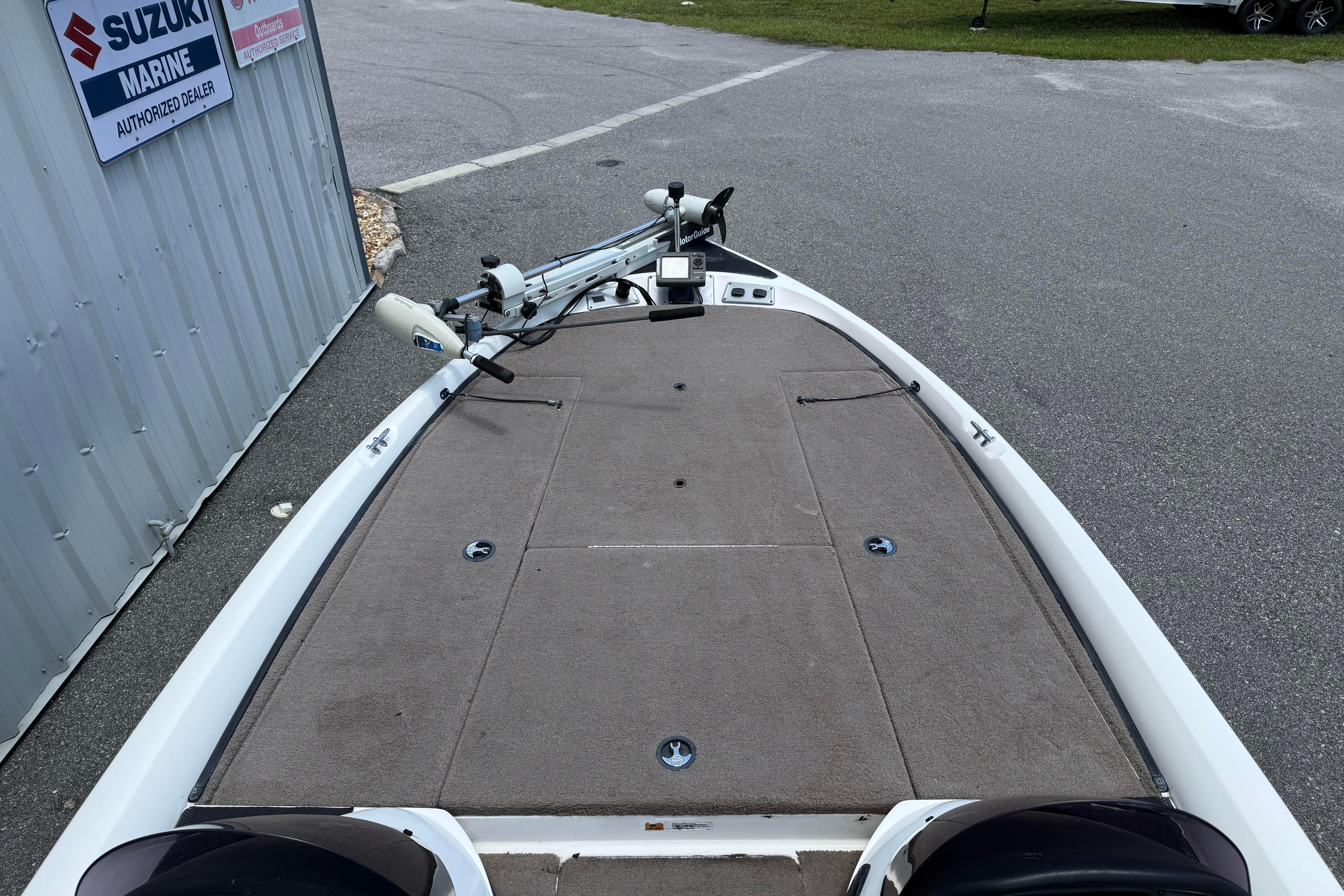 2006 Stratos 294 Pro XL boat deck with trolling motor, parked near Suzuki Marine dealer.