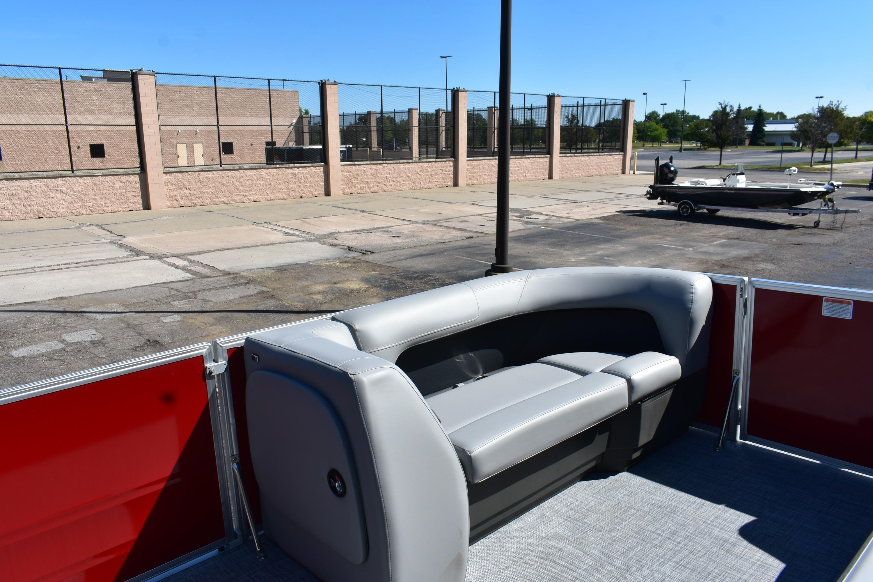 2026 Sun Tracker Party Barge 18 DLX with gray seating, parked near a brick building.