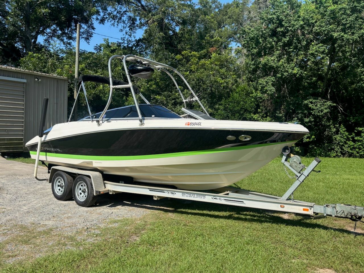 A 2006 Regal 2200 Bowrider on a trailer, surrounded by trees and grass.