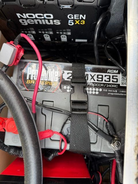 Battery and charger in a boat, with cables and securing straps.