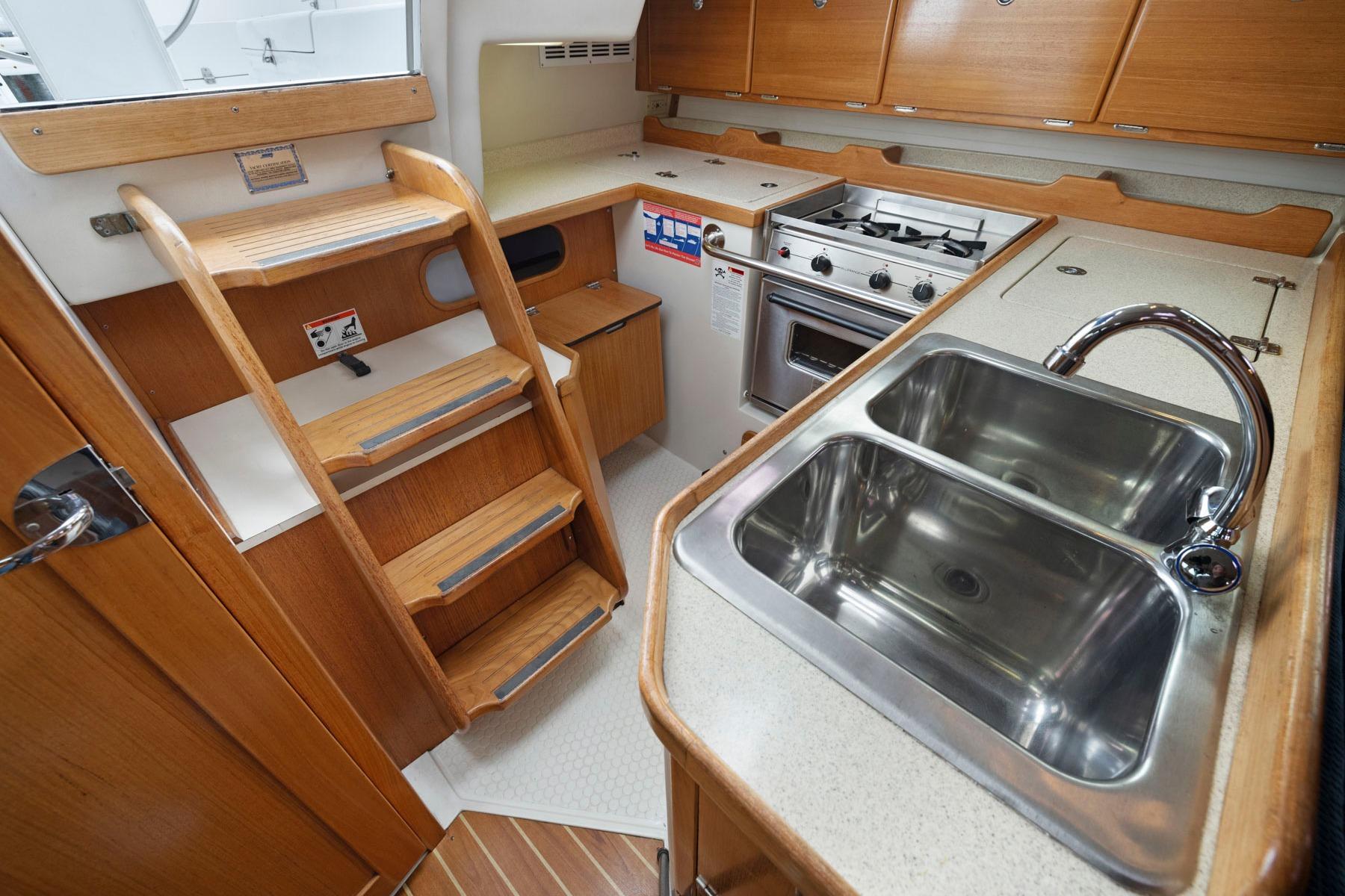 2004 Catalina 36 MkII yacht interior with wooden cabinetry, dual sink, and compact kitchen.