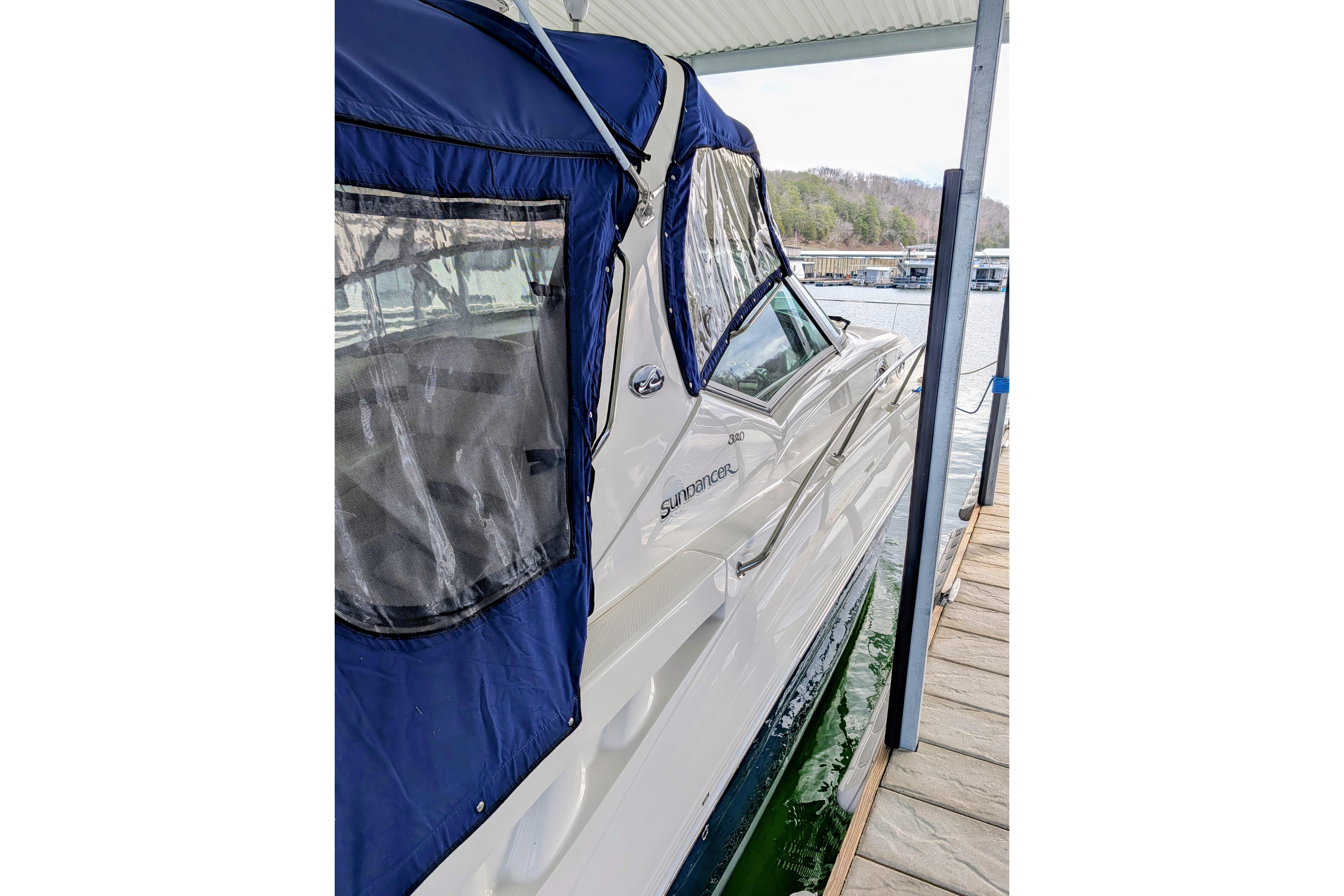 2005 Sea Ray Sundancer 320 docked, featuring blue canopy and sleek design.