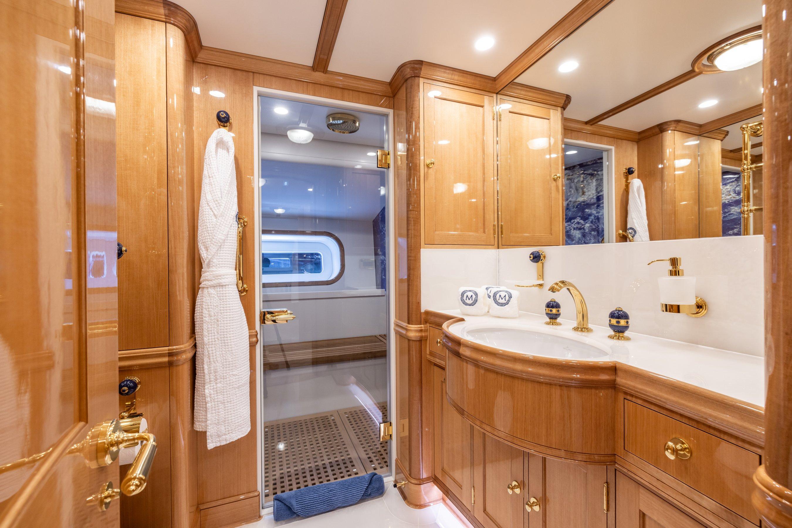 Luxurious 2023 Vitters Cruising Ketch bathroom with elegant wood cabinetry and gold fixtures.