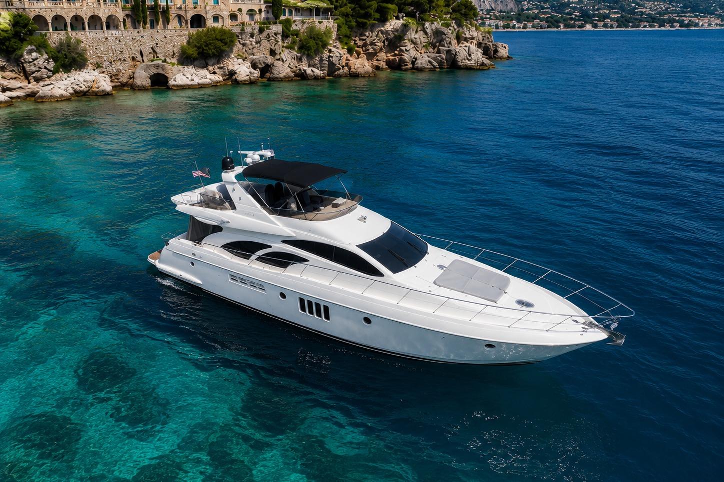 Luxurious 2004 Azimut 55E yacht cruising in clear blue waters near rocky coastline.