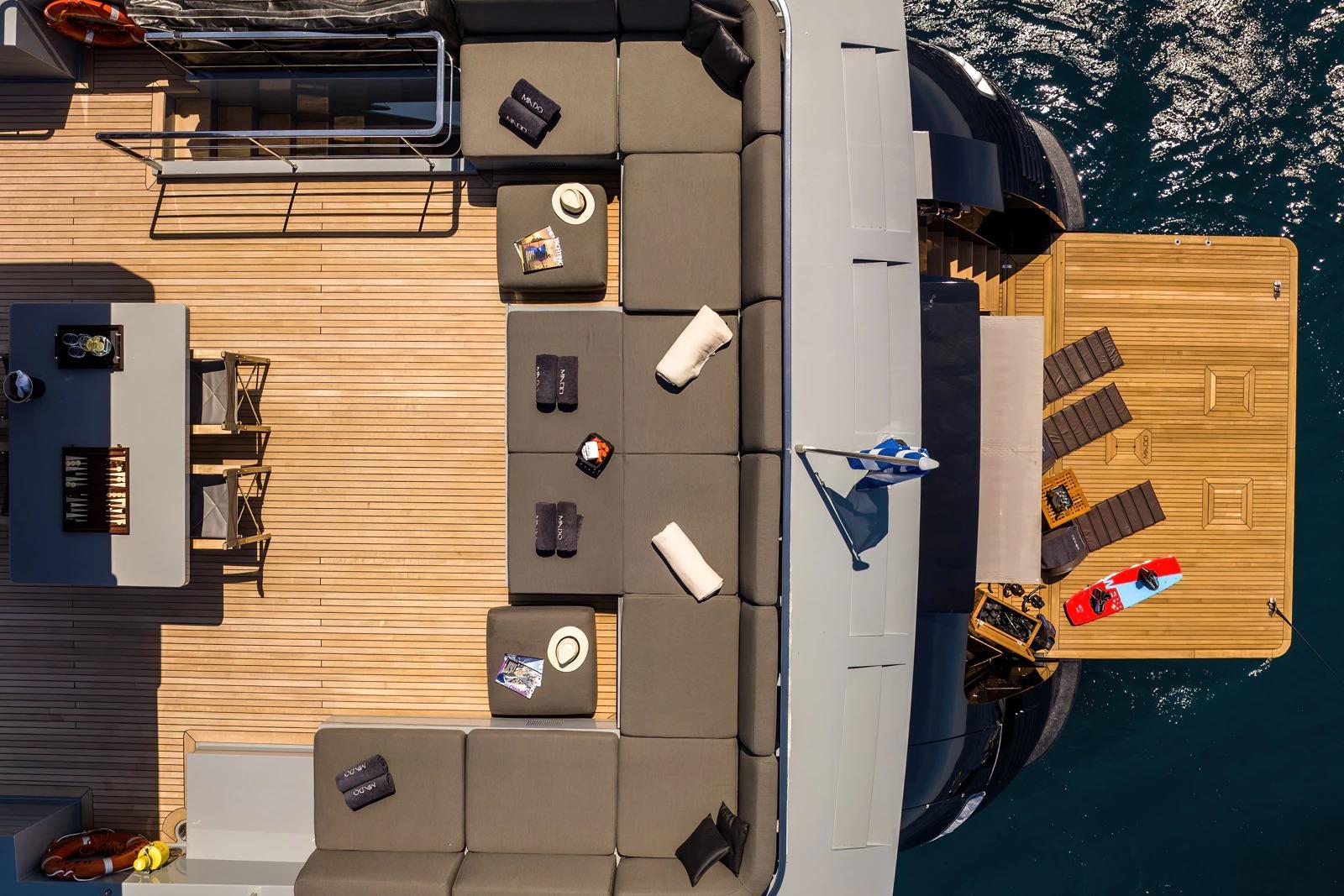Luxurious Admiral 2009 yacht deck with seating, table, and sun loungers by the water.